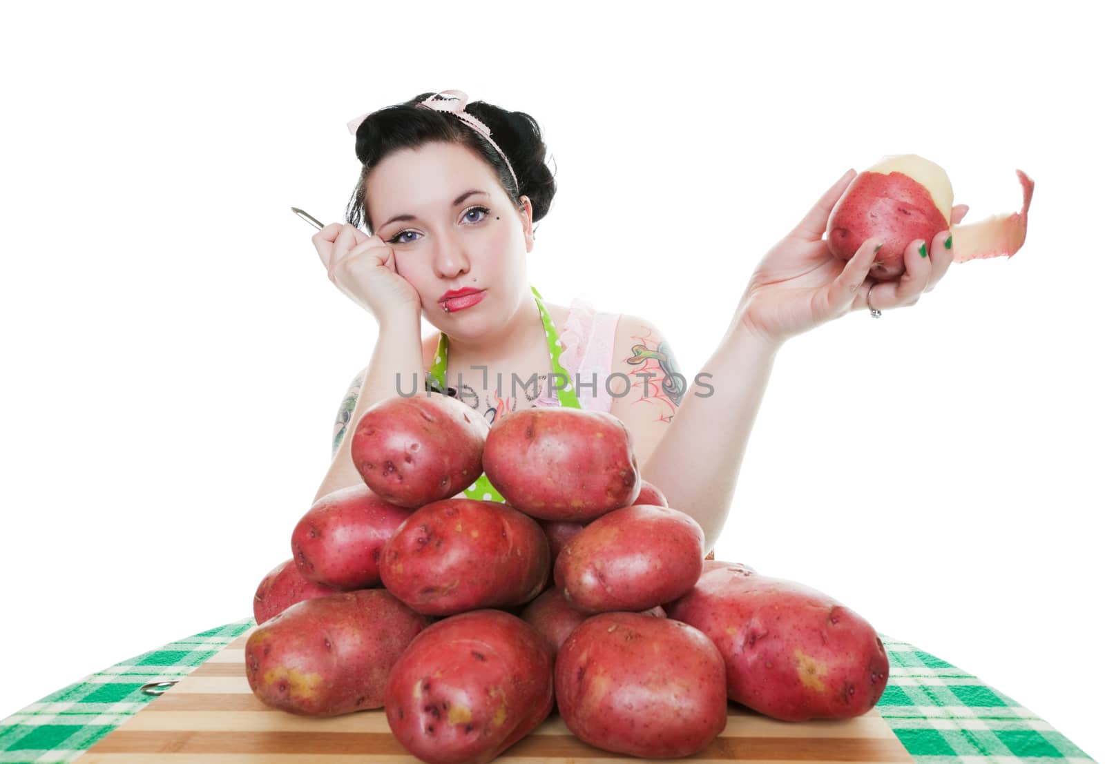 A young, rockabilly housewife depressed about the huge amount of potatoes she has to peel.  Shot on white background.