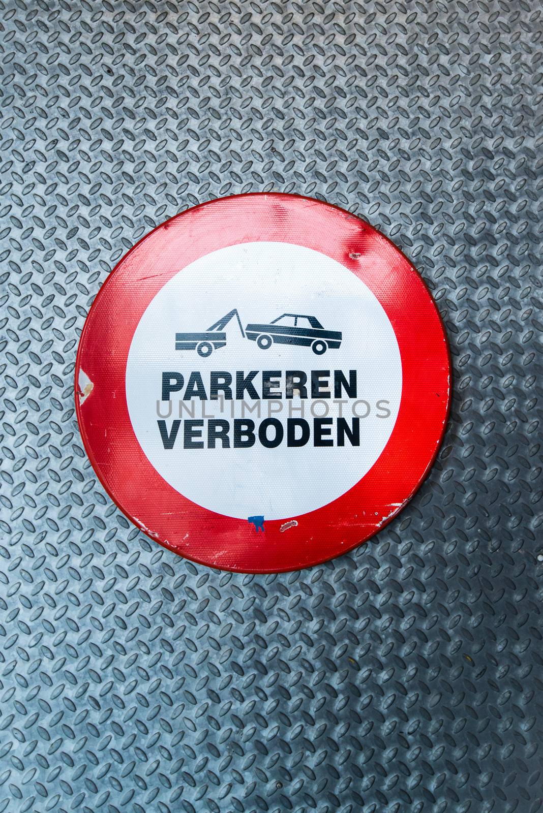Dutch no parking sign with wording "parkeren verboden" and a car being towed away on metal door background