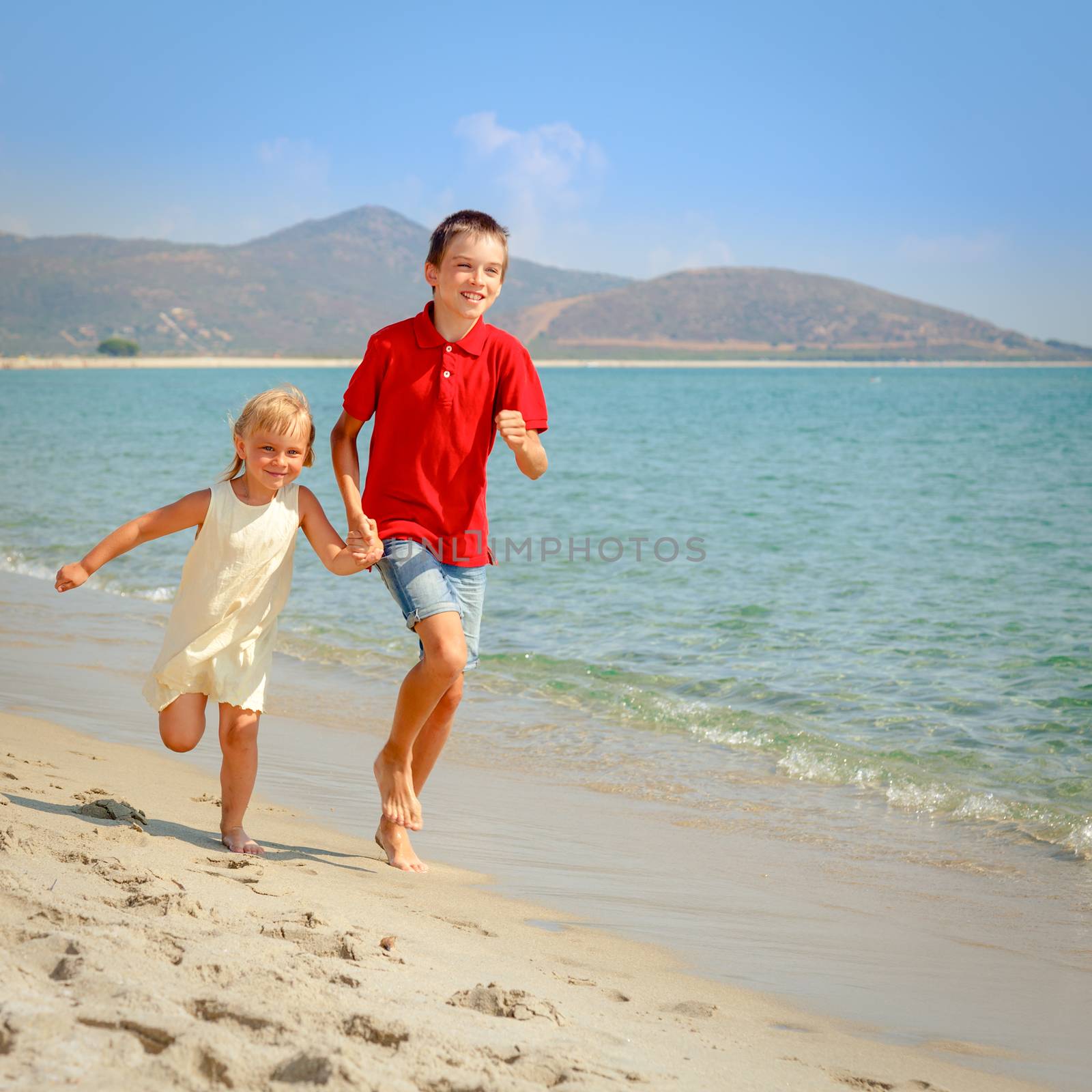 Happy children running along a beach