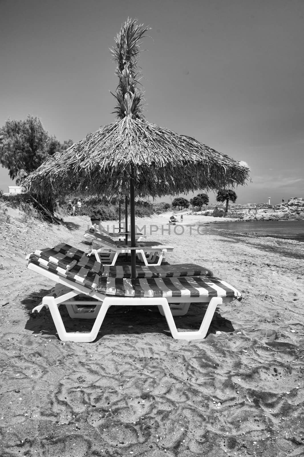 Relaxing sunbeds on the beach under straw umbrella.