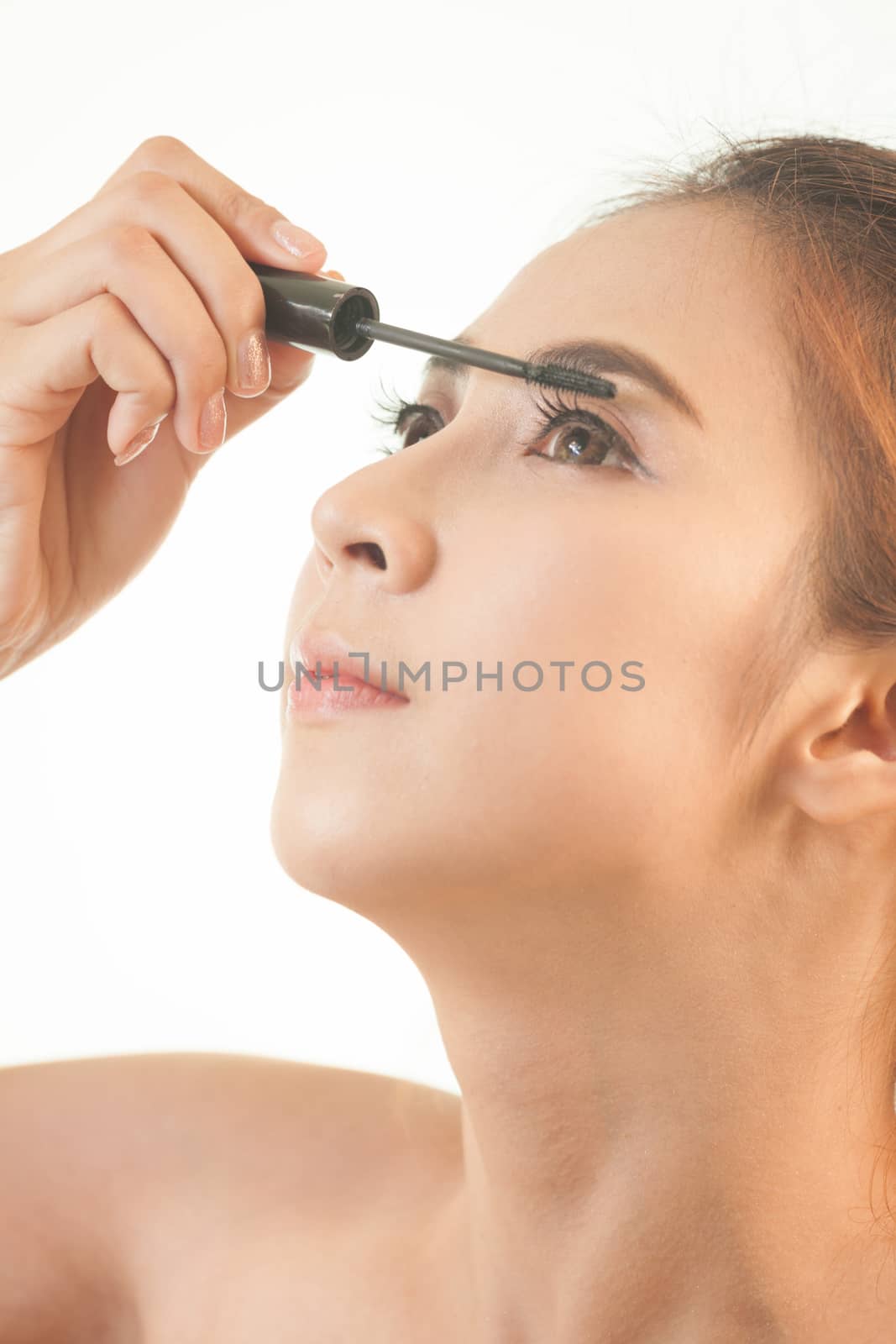 Young asian woman applying mascara on her long eyelashes isolated on white background