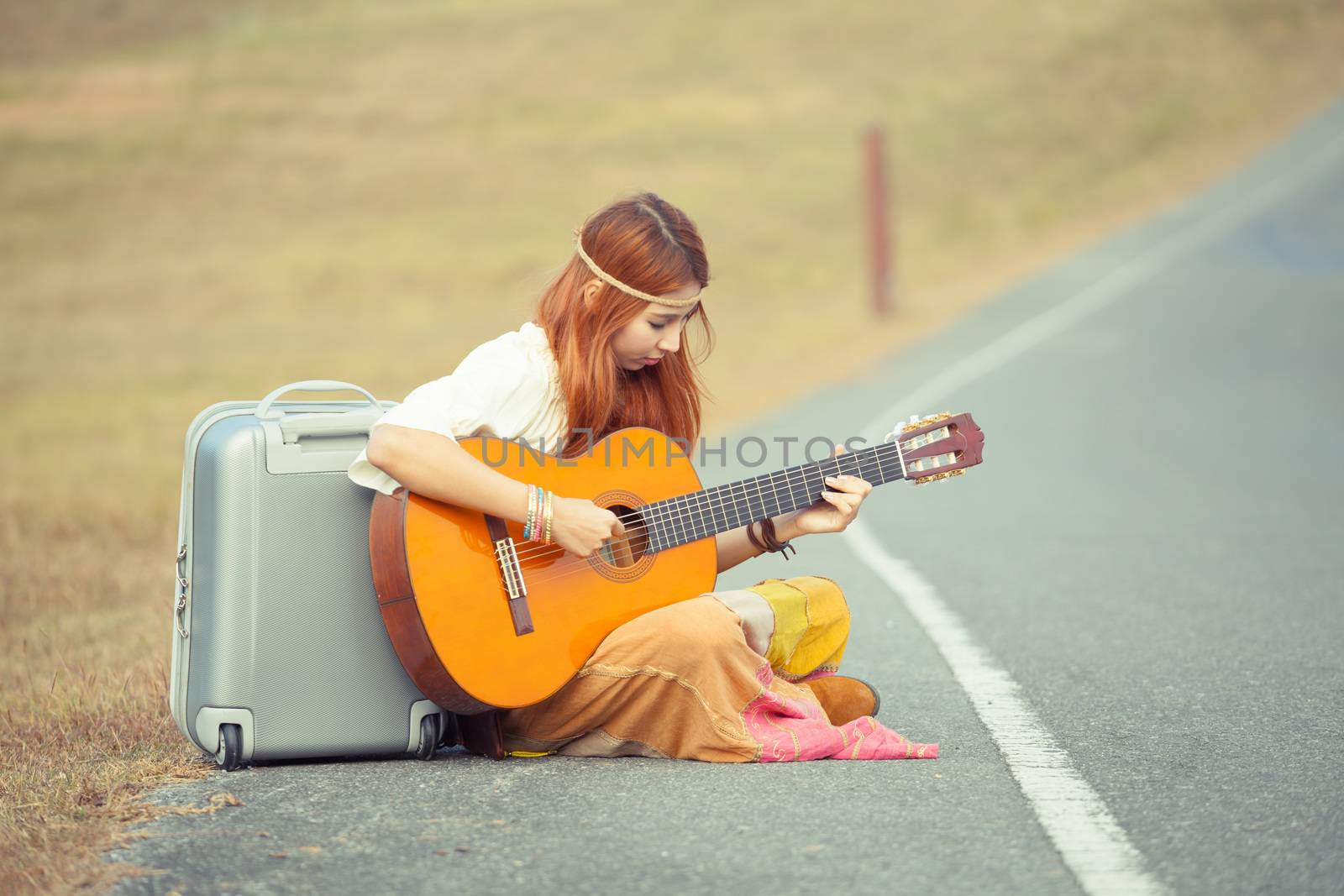 Hippie woman playing music on the country road