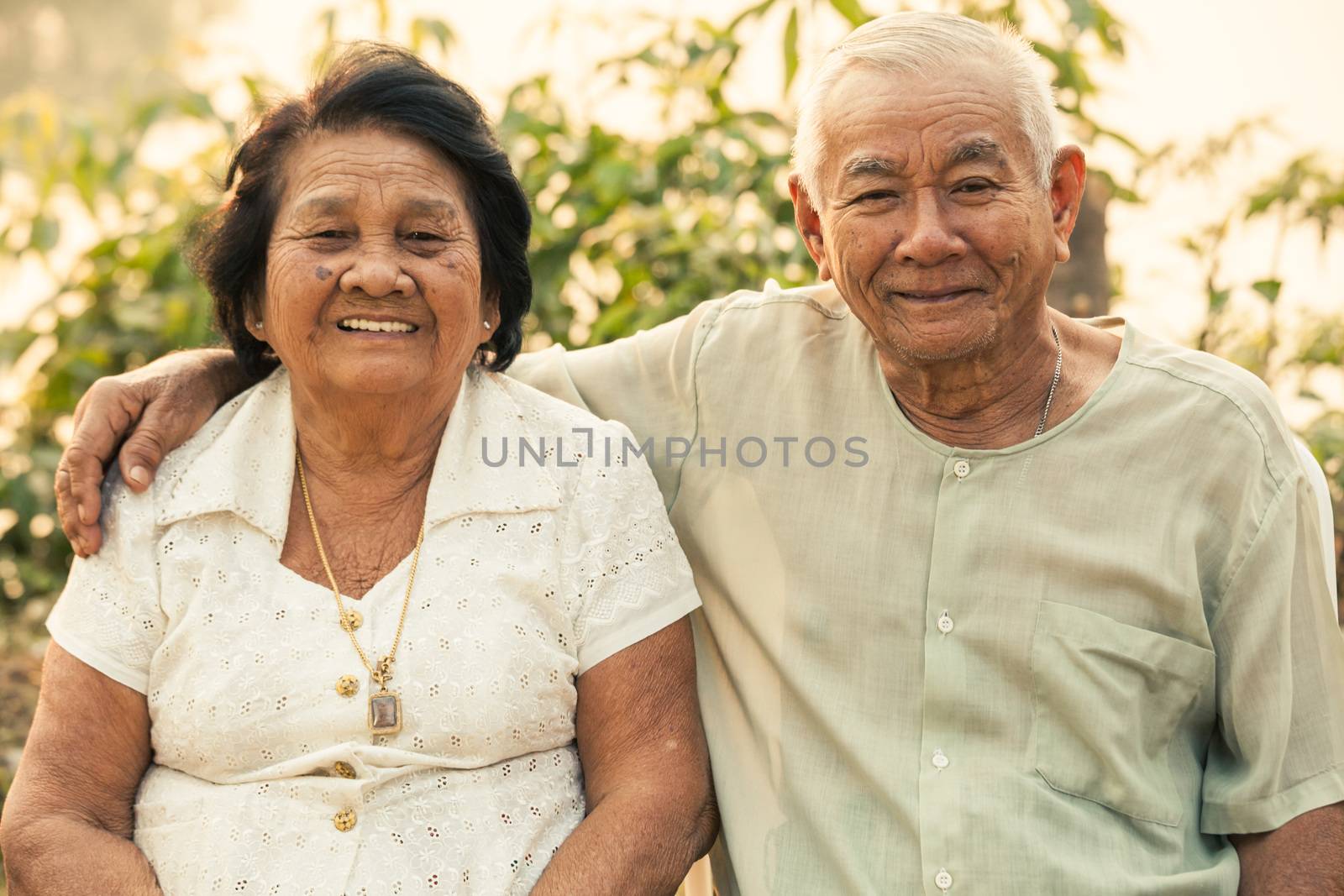 Happy Asian Senior couple sitting outdoors on sunset