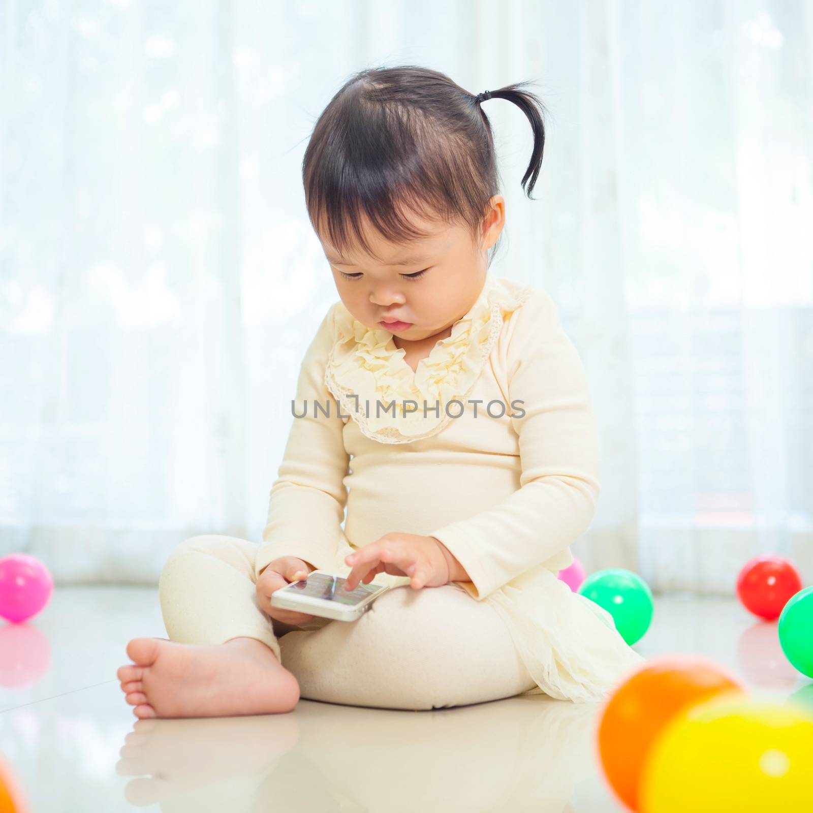 Happy little asian girl using mobile phone in the home