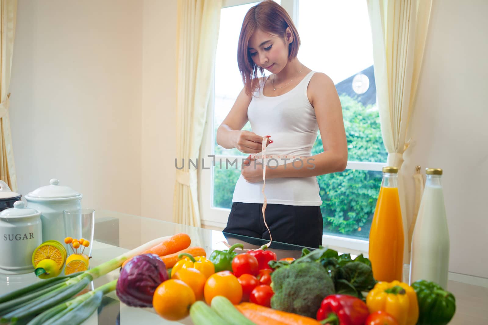 Young asian woman measuring her stomach