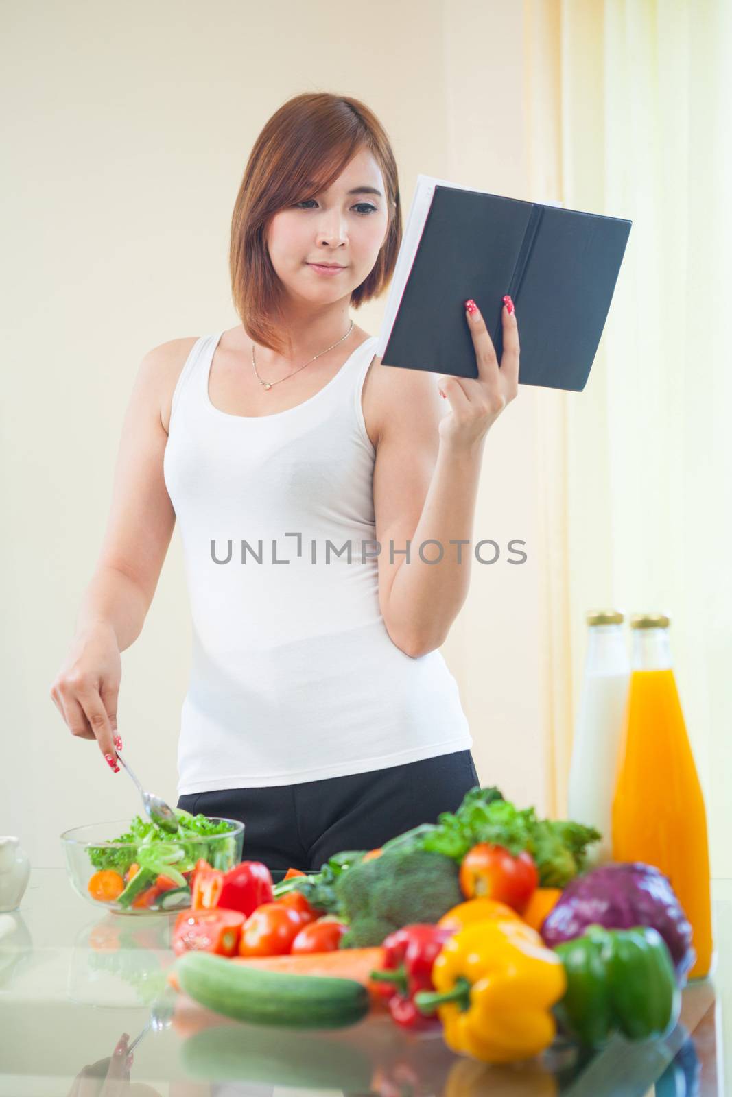 Young asian woman reads cookbook for recipe at kitchen