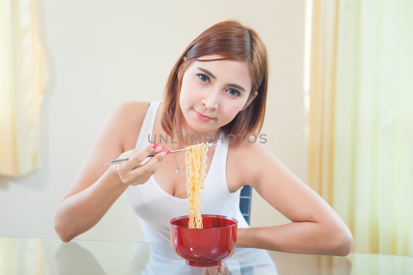 Young Asian girl eating ramen noodles using chopsticks