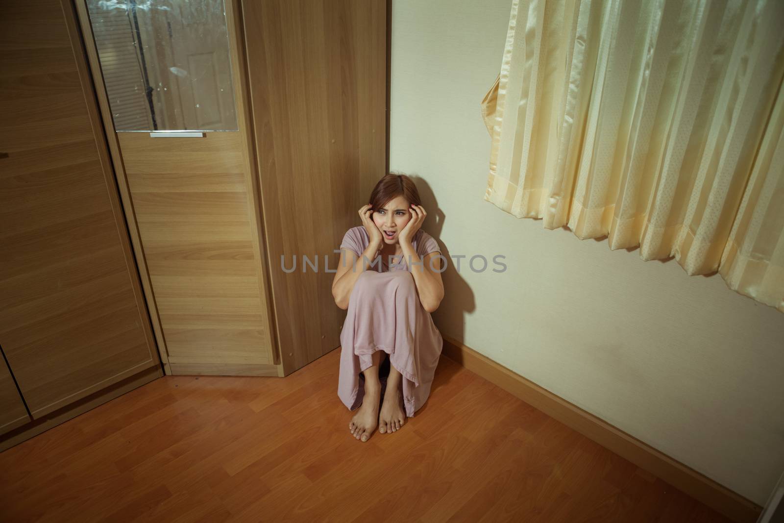 Scared abused woman sitting in the corner of the room