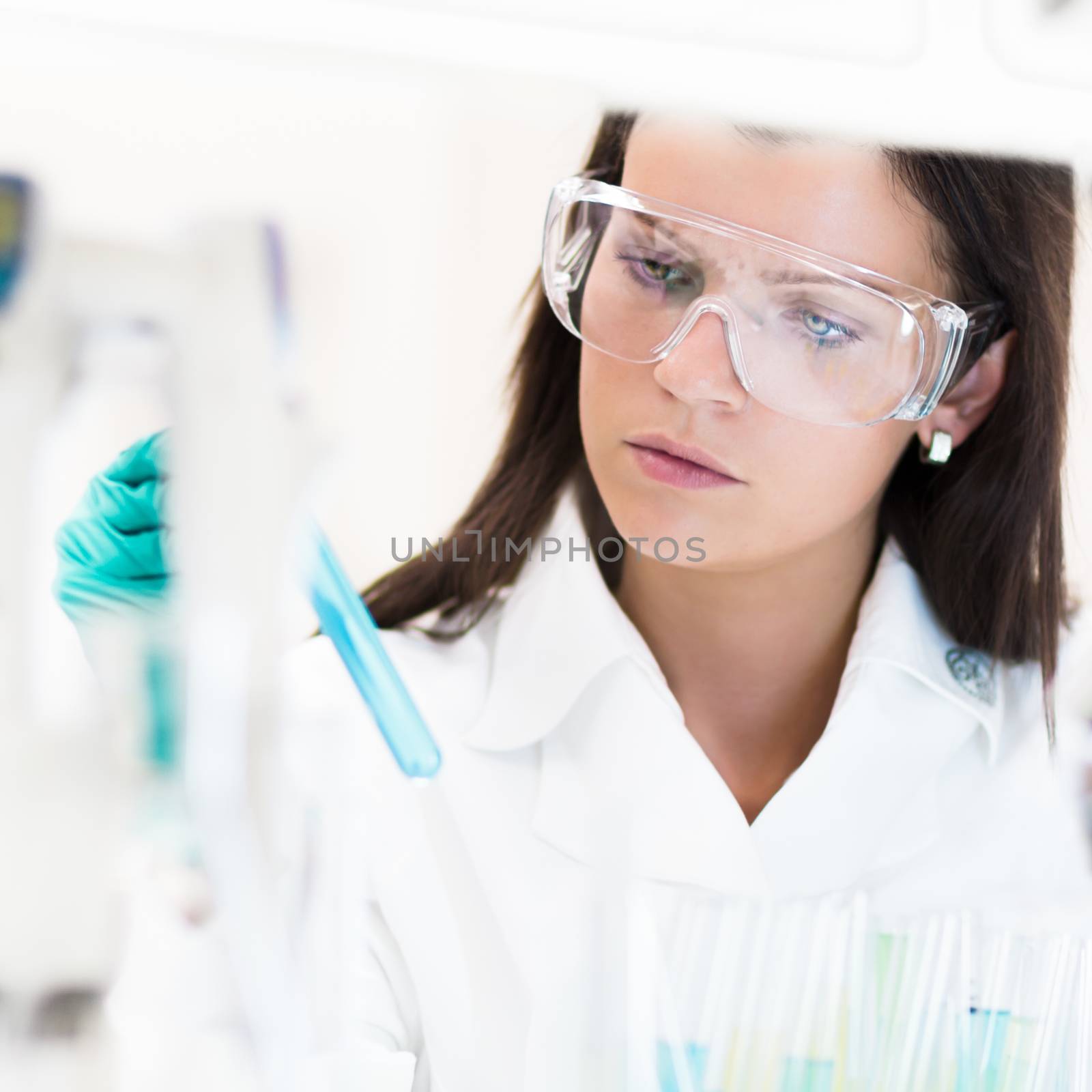 Attractive young PhD student scientist looking at the microscope slide in the life science research laboratory (biochemistry, genetics, forensics, microbiology ..)