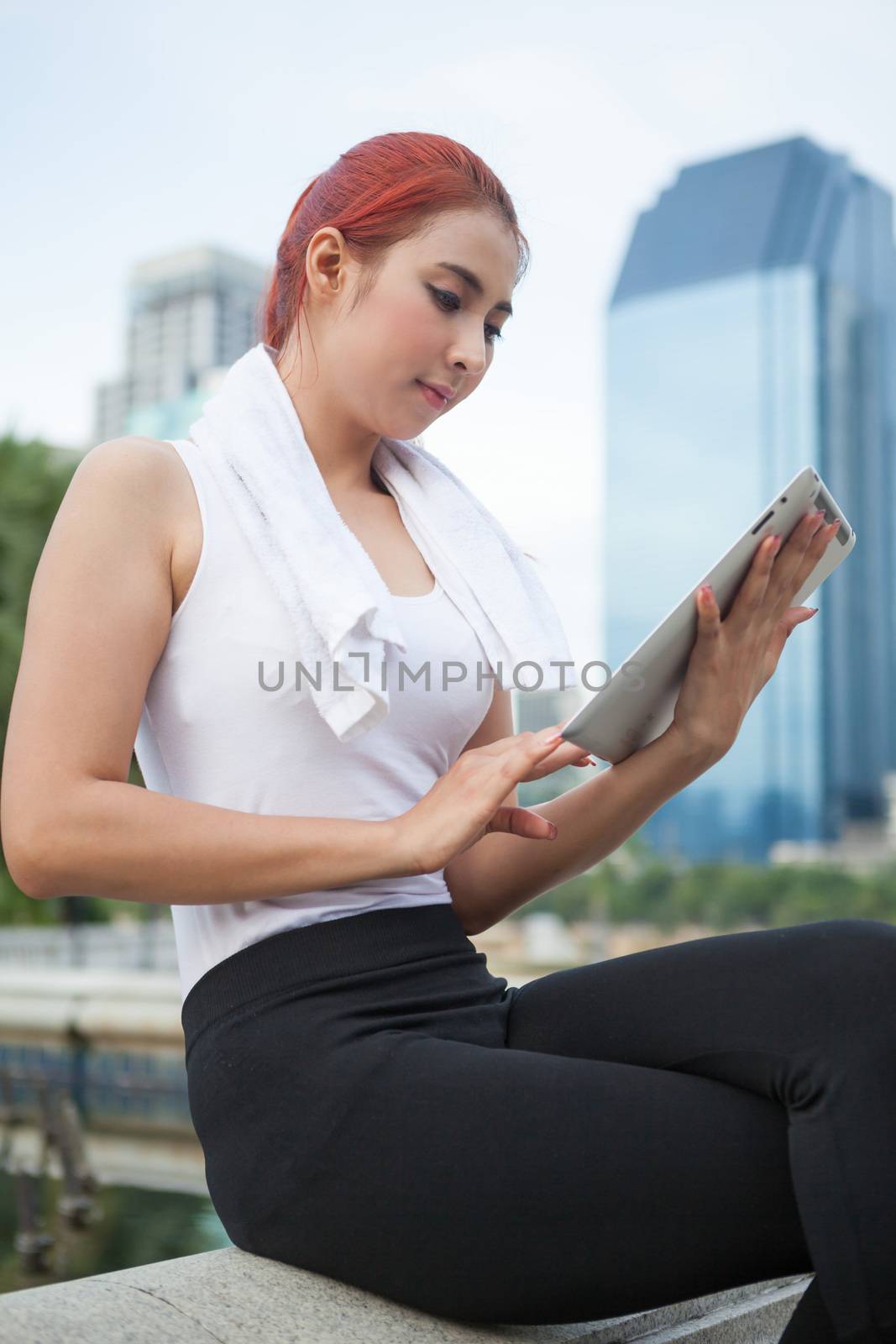 beautiful fitness asian woman with tablet in park city