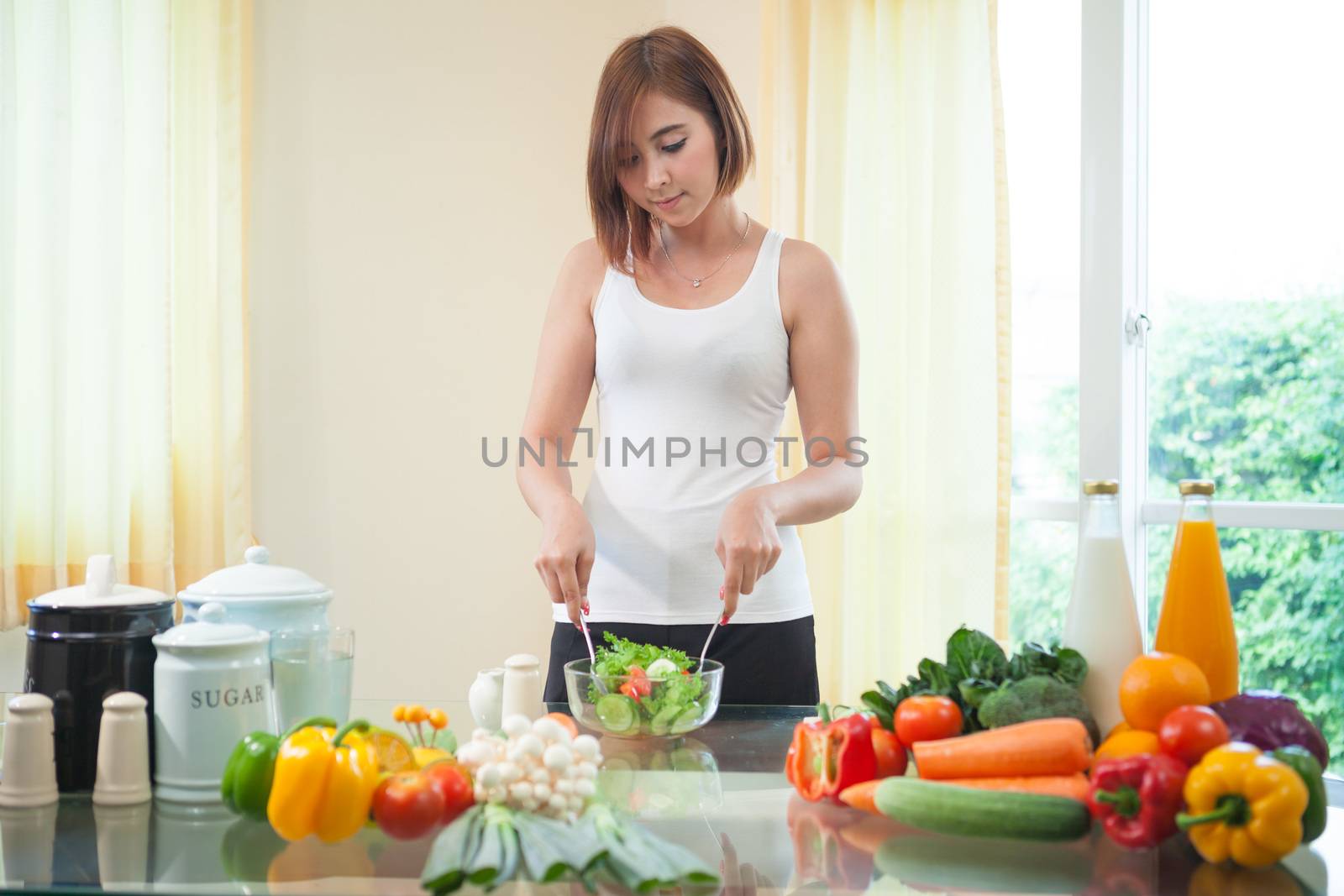 Happy asian woman cooking vegetables green salad in the kitchen