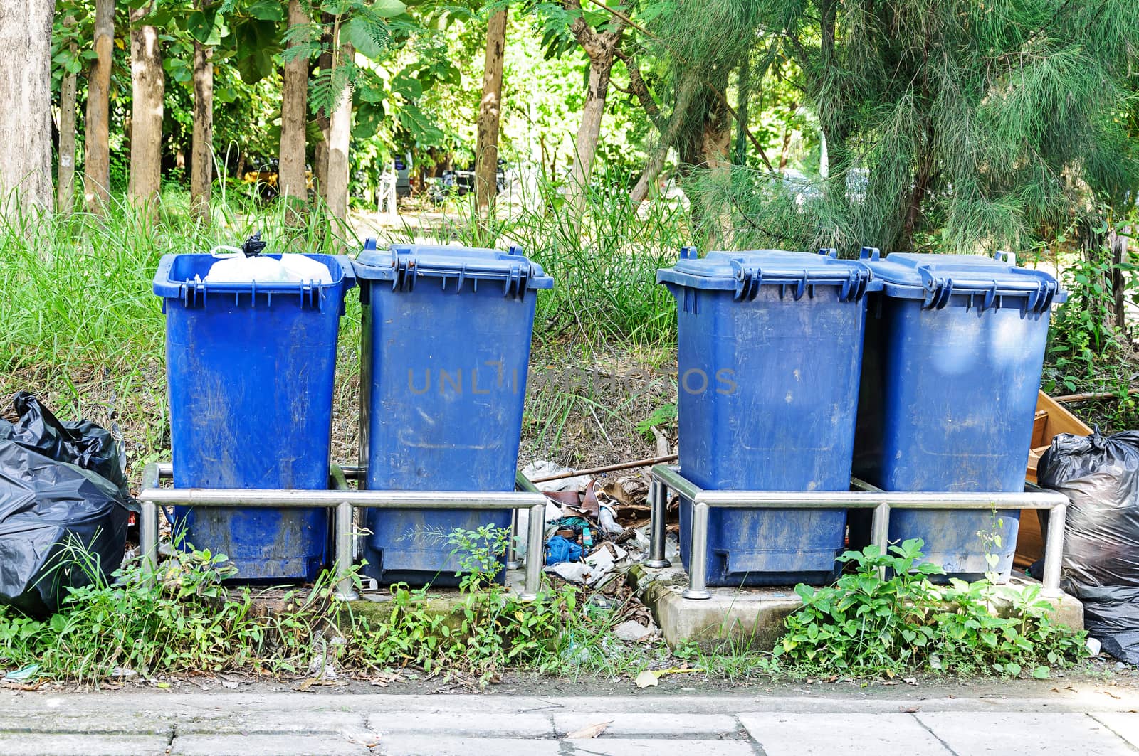 Group of blue garbage cans on the side of the road 
