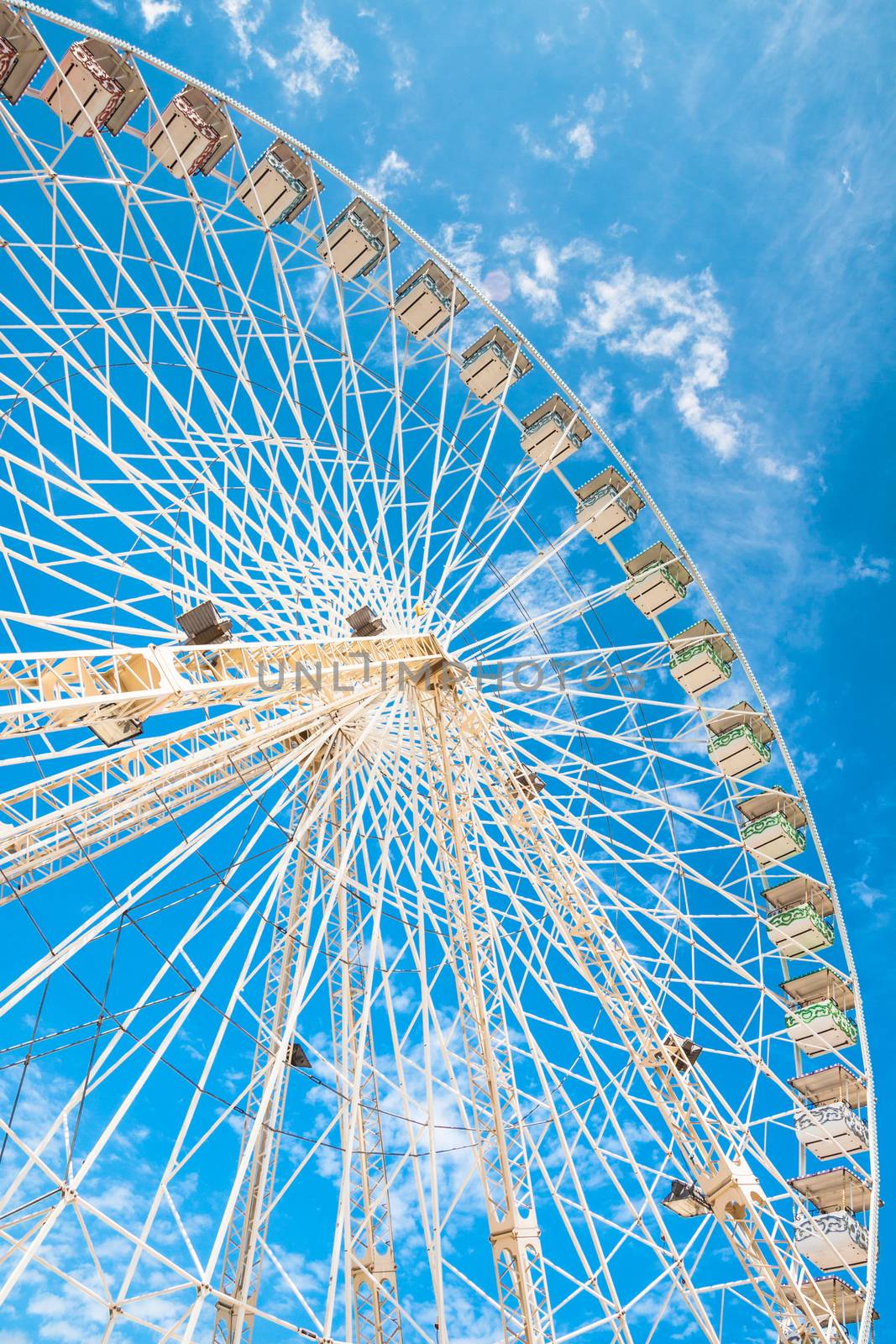 Ferris wheel of fair and amusement park.  White clouds in the blue sky in background.