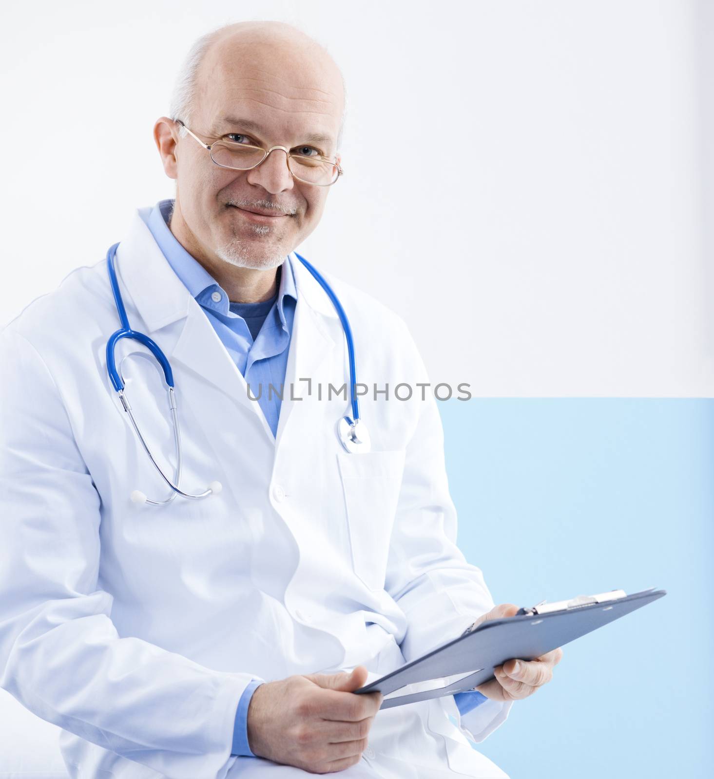 Friendly confident doctor sitting on a medical examination bed.