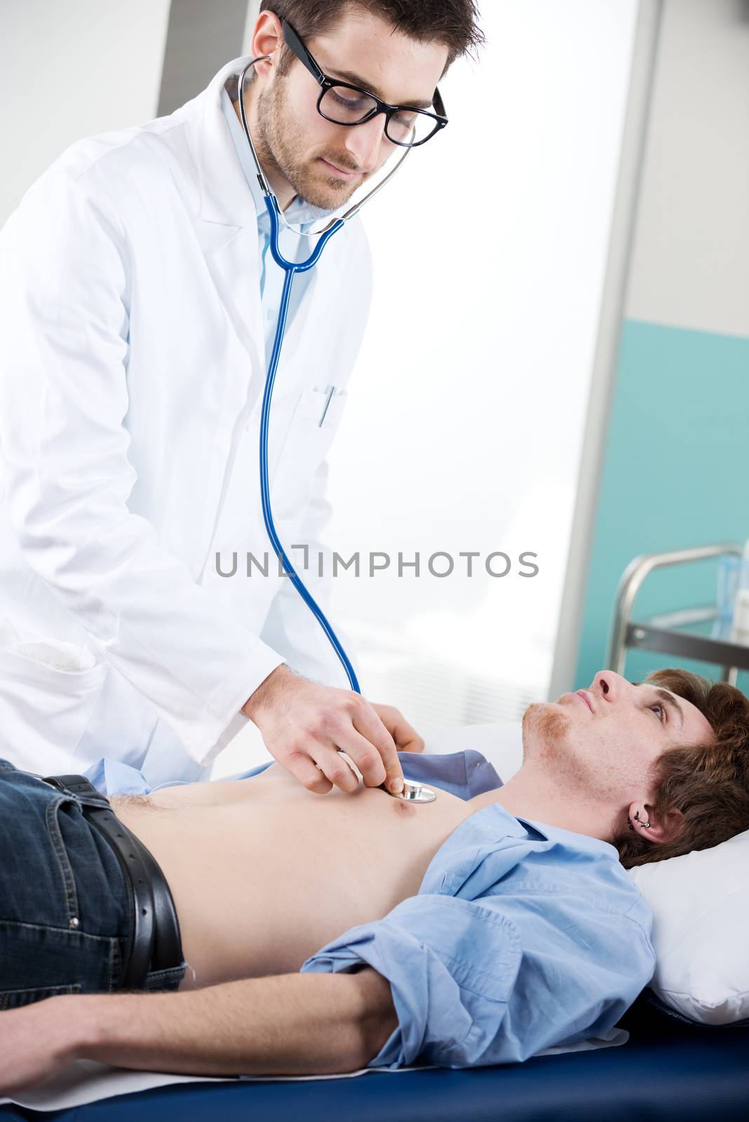 Doctor vising carefully a patient with a stethoscope on a medical examination table.