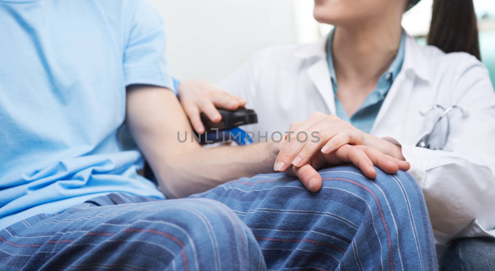 Young female doctor comforting a young patient on wheelchair.