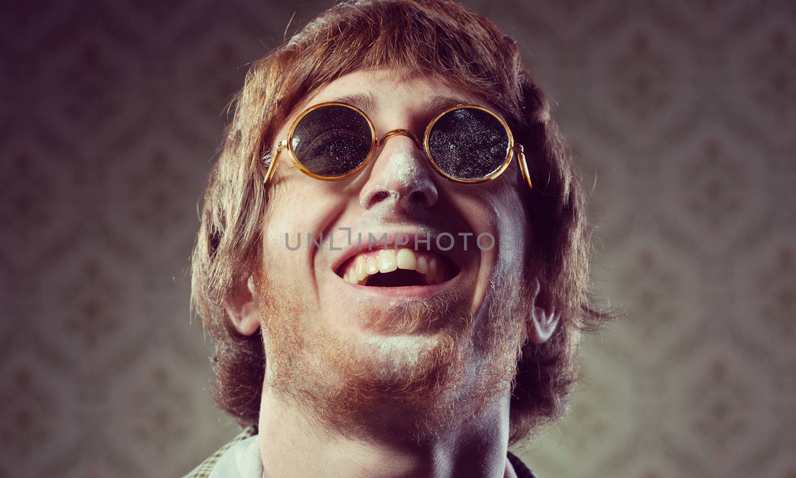 Funny 1960s style guy after snorting cocaine on vintage wallpaper background.