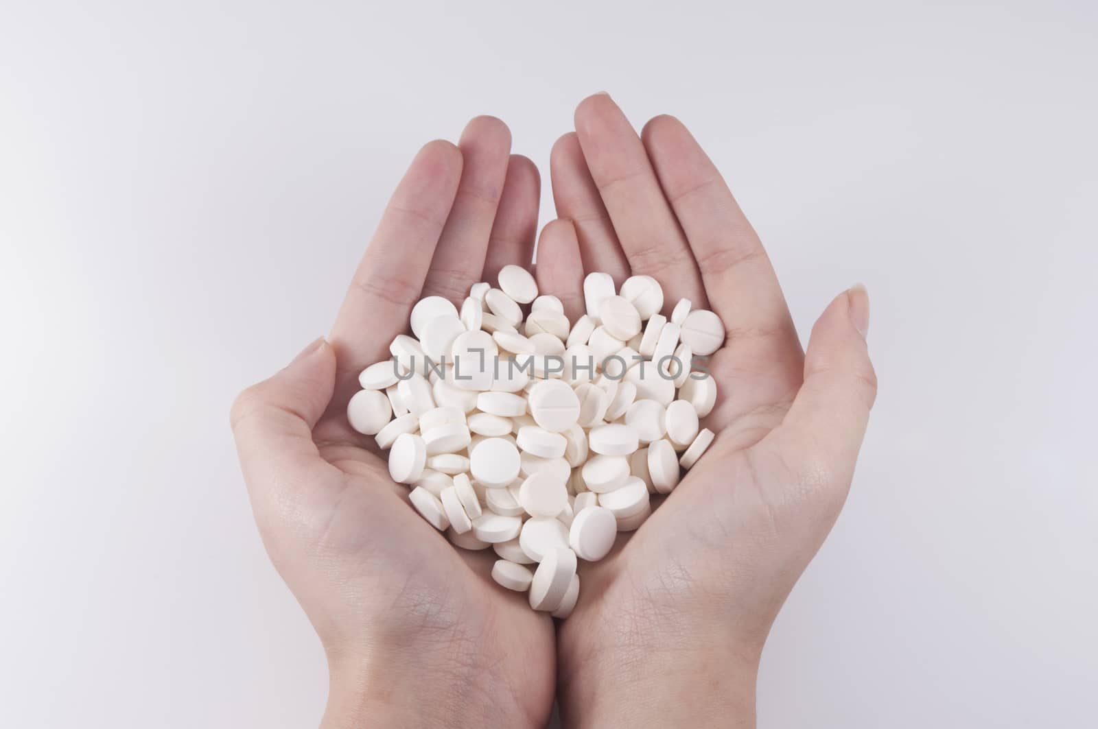 Caucasian Woman Holding a Bunch of Pills and Capsules on White B by rodrigobellizzi