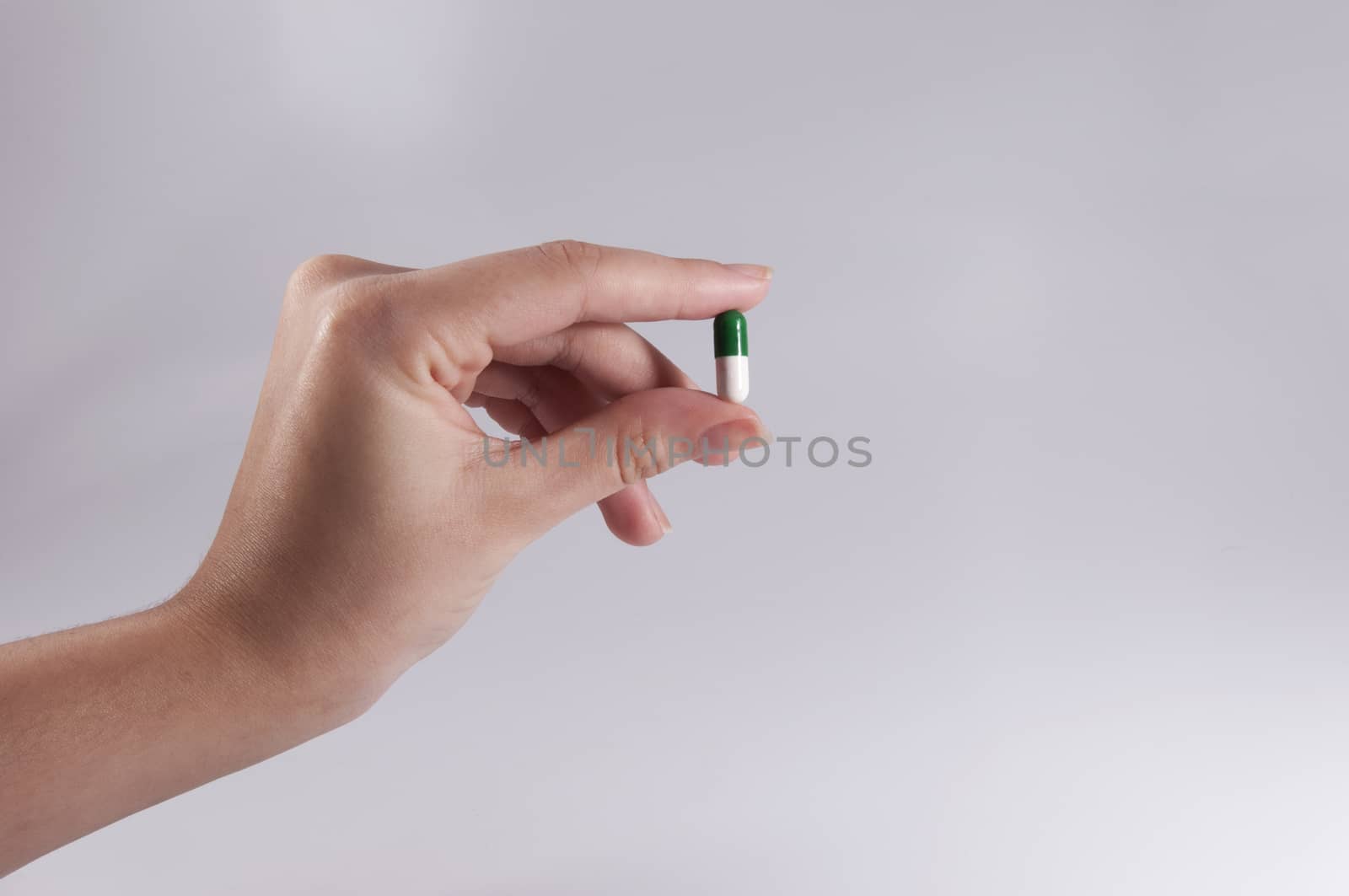 Caucasian Woman Holding a Pill on White Background / Capsules and Pills / Medicine