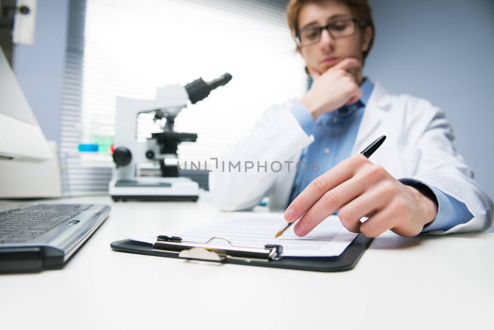 Young researcher writing notes at desk in the chemical lab.