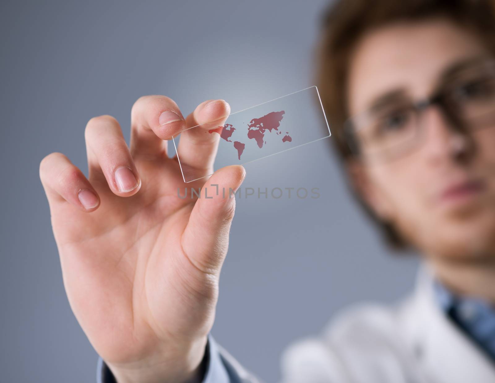 Researcher holding a microscope slide with world map.