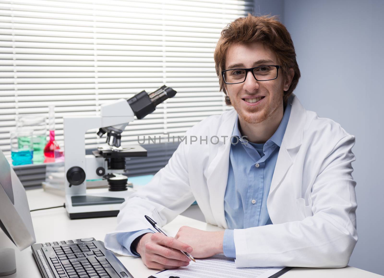 Young researcher writing notes at desk in the chemical lab.