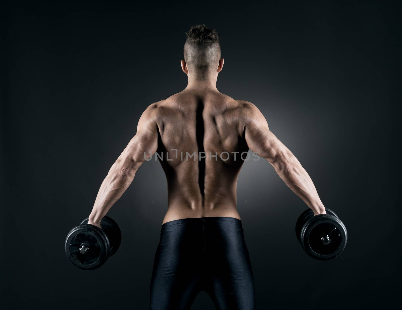 Muscular attractive man weightlifting on dark background.