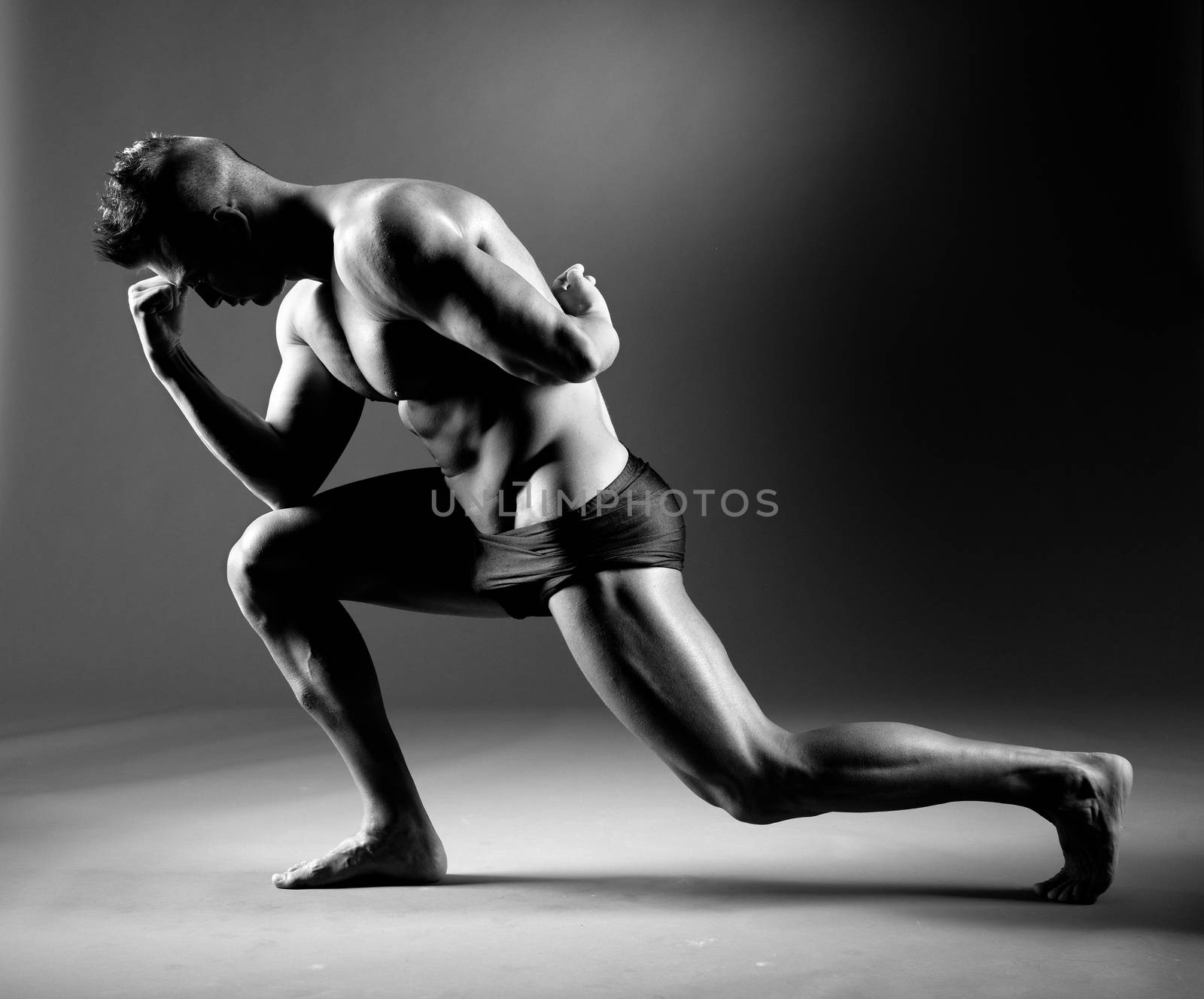 Body builder posing and showing off bicep muscle on dark background.