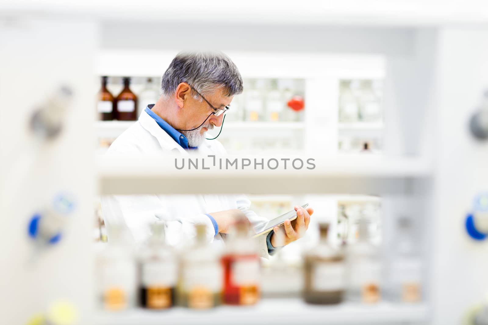 Senior doctor/scientist using his tablet computer at work (color toned image)