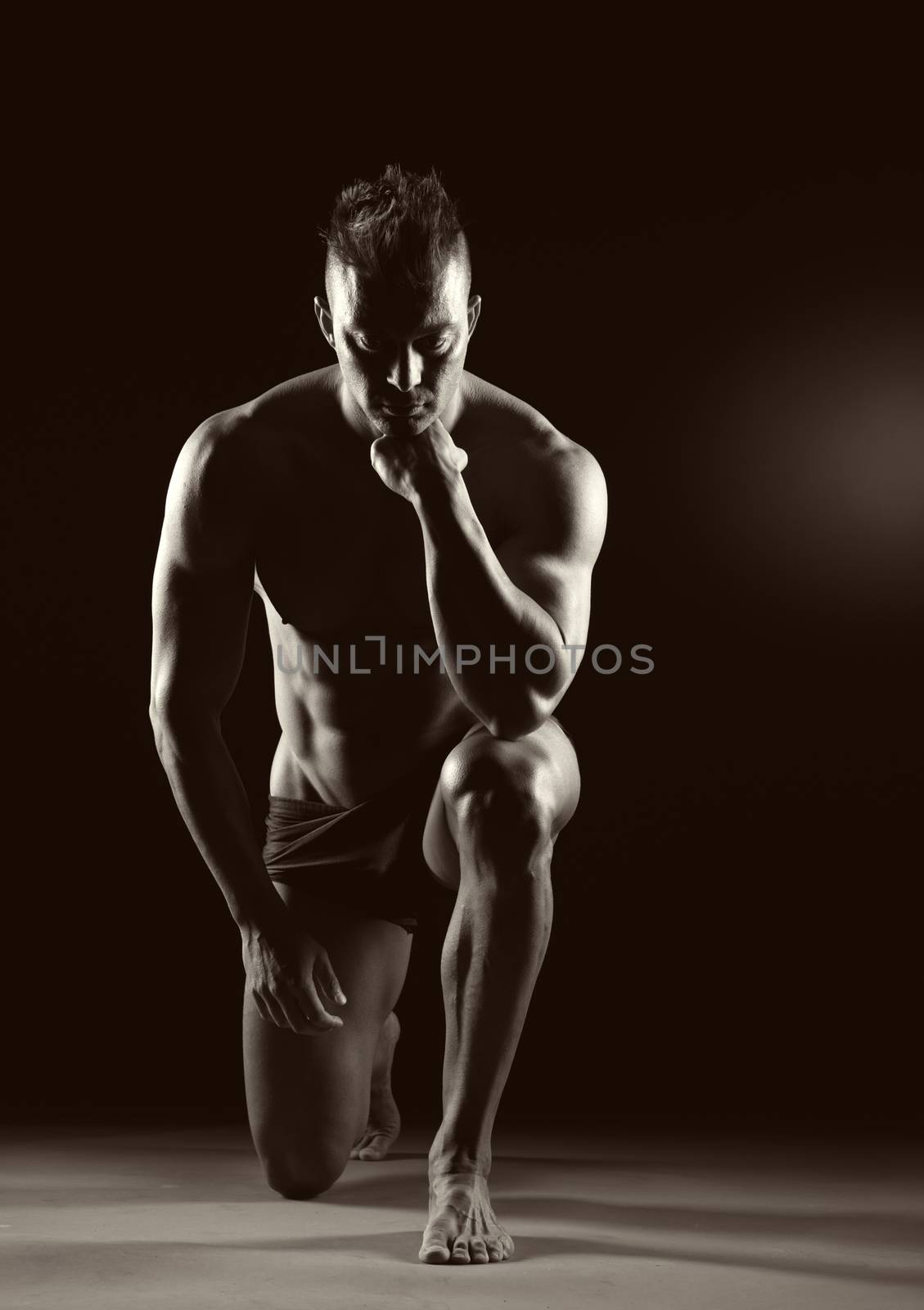 Body builder posing and showing off bicep muscle on dark background.