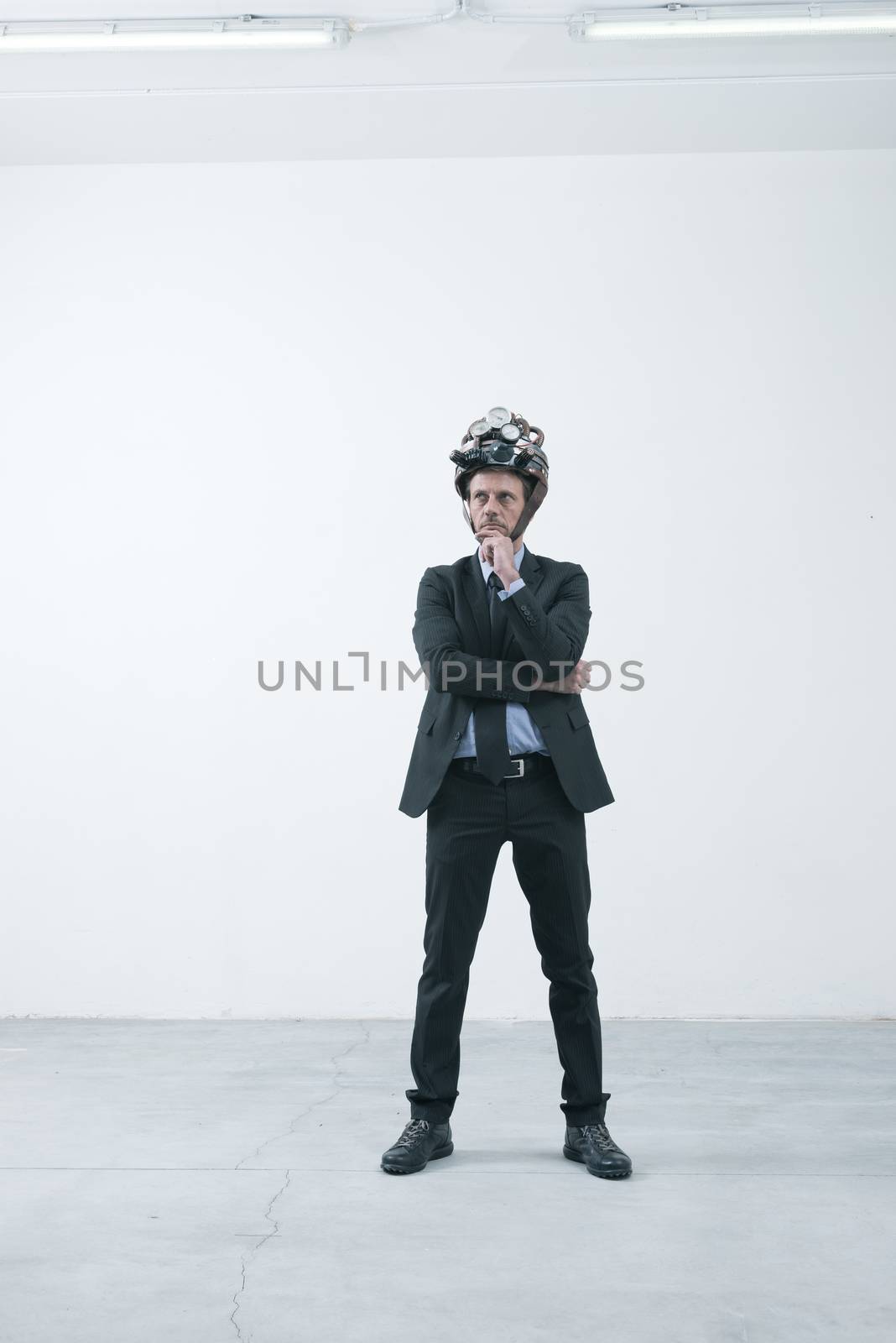 Confident businessman thinking with hand on chin wearing steampunk helmet 