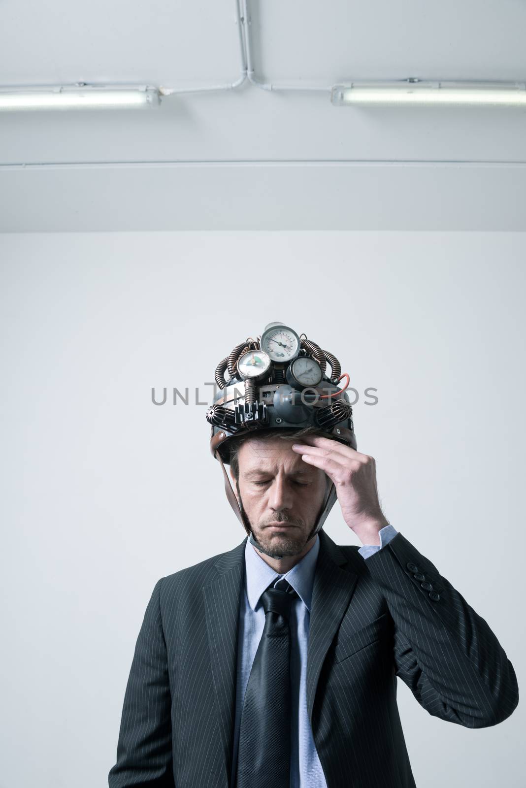 Tired pensive businessman touching his forehead weaaring futuristic helmet with gauges.