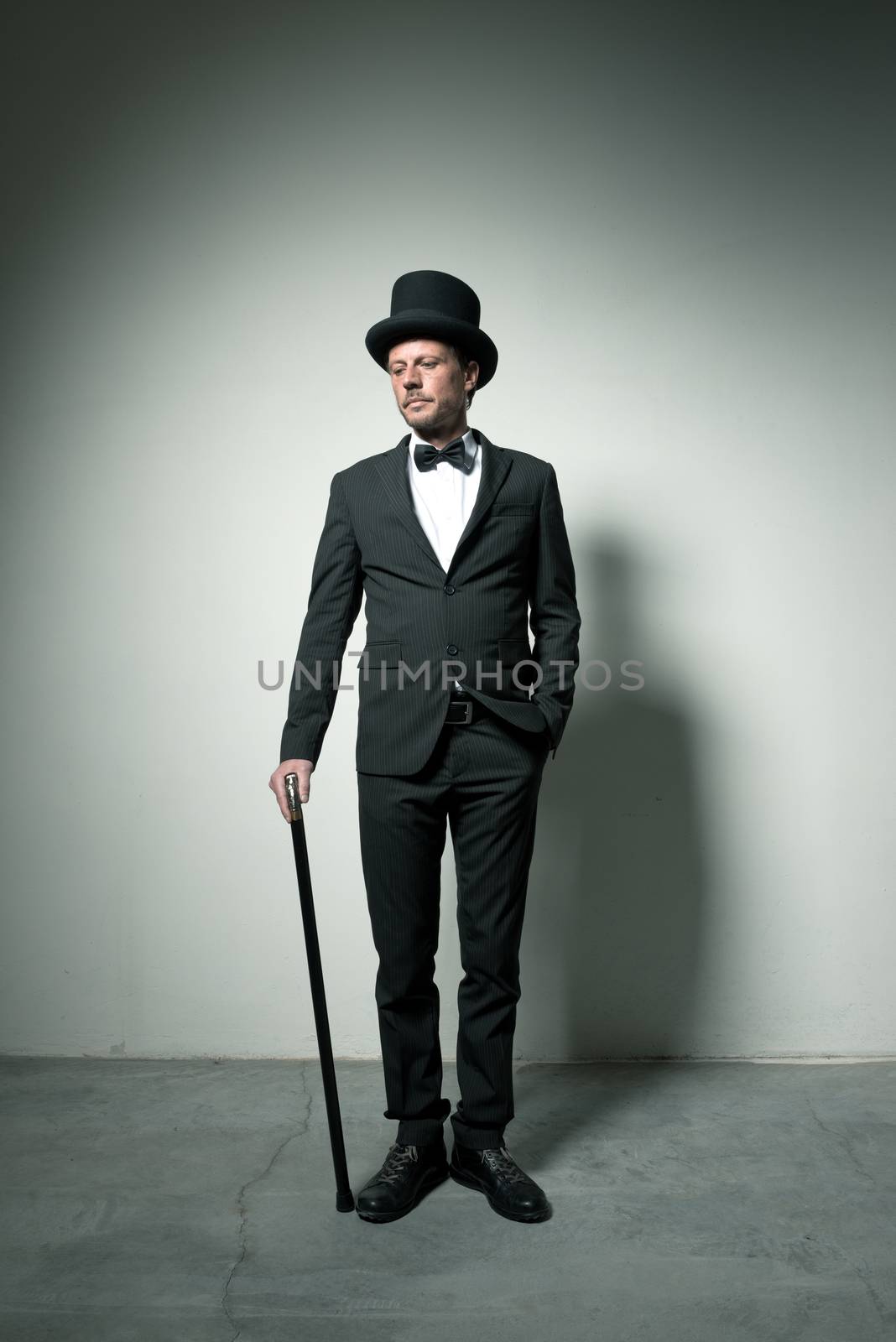 Classy gentleman with bowler hat and cane looking down