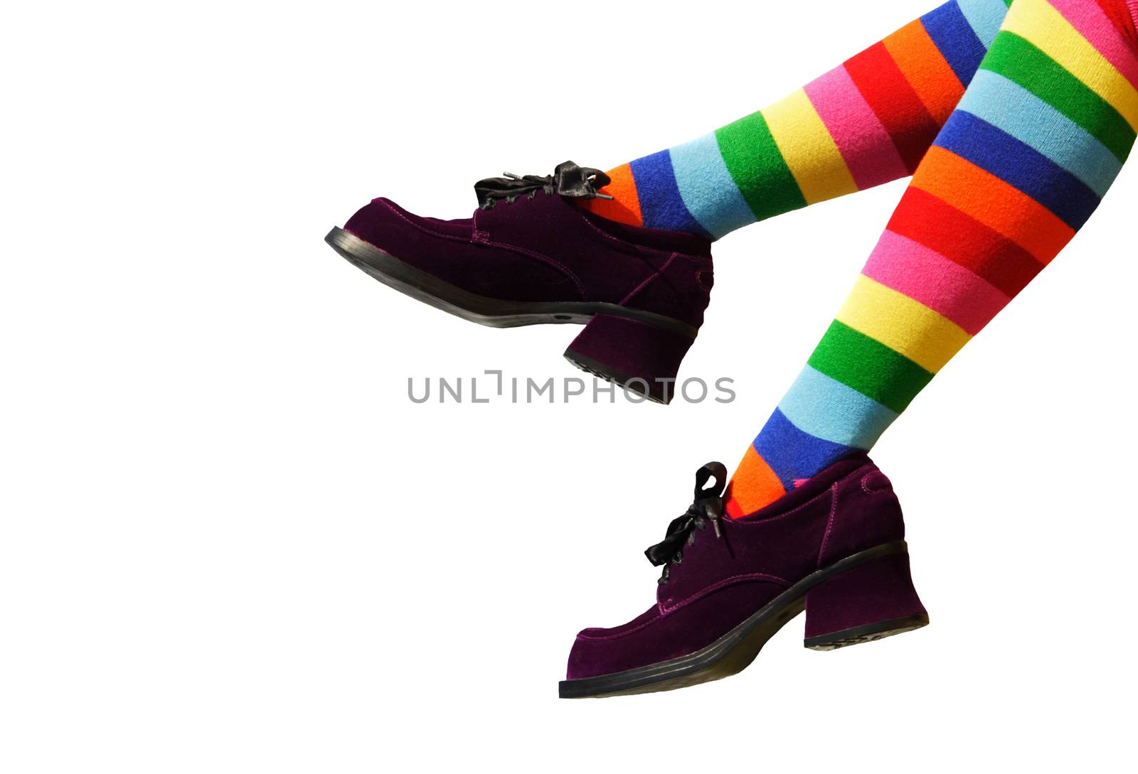 Striped knee-hi socks and wickedly wonky, purple suede shoes on isolated girl's legs.
