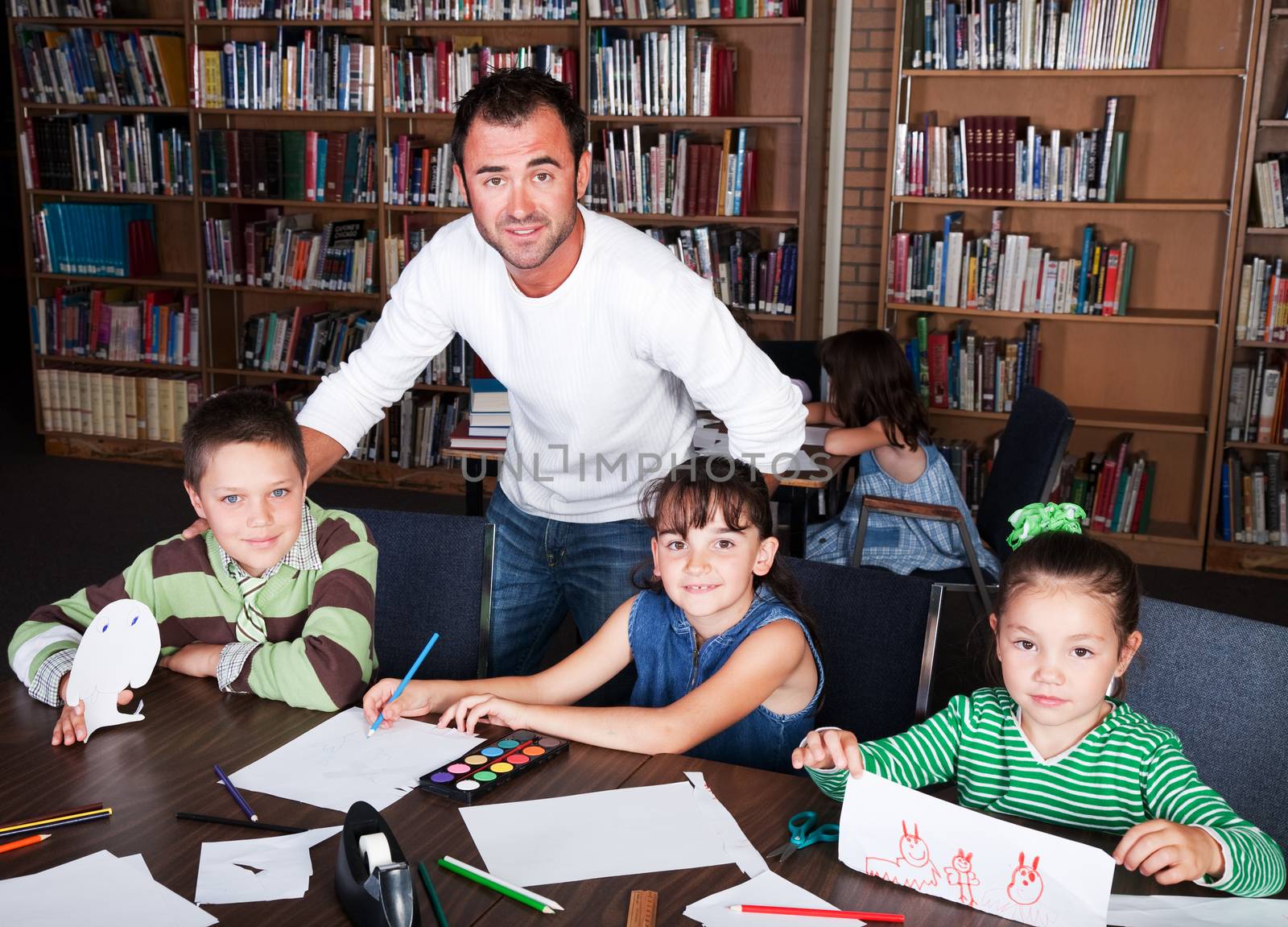 A teacher guides his students in an art class in the school library.