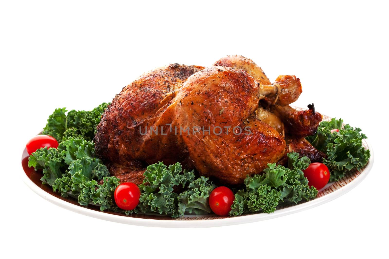 A beautiful roasted chicken on a garnished platter.  Shot on white background.