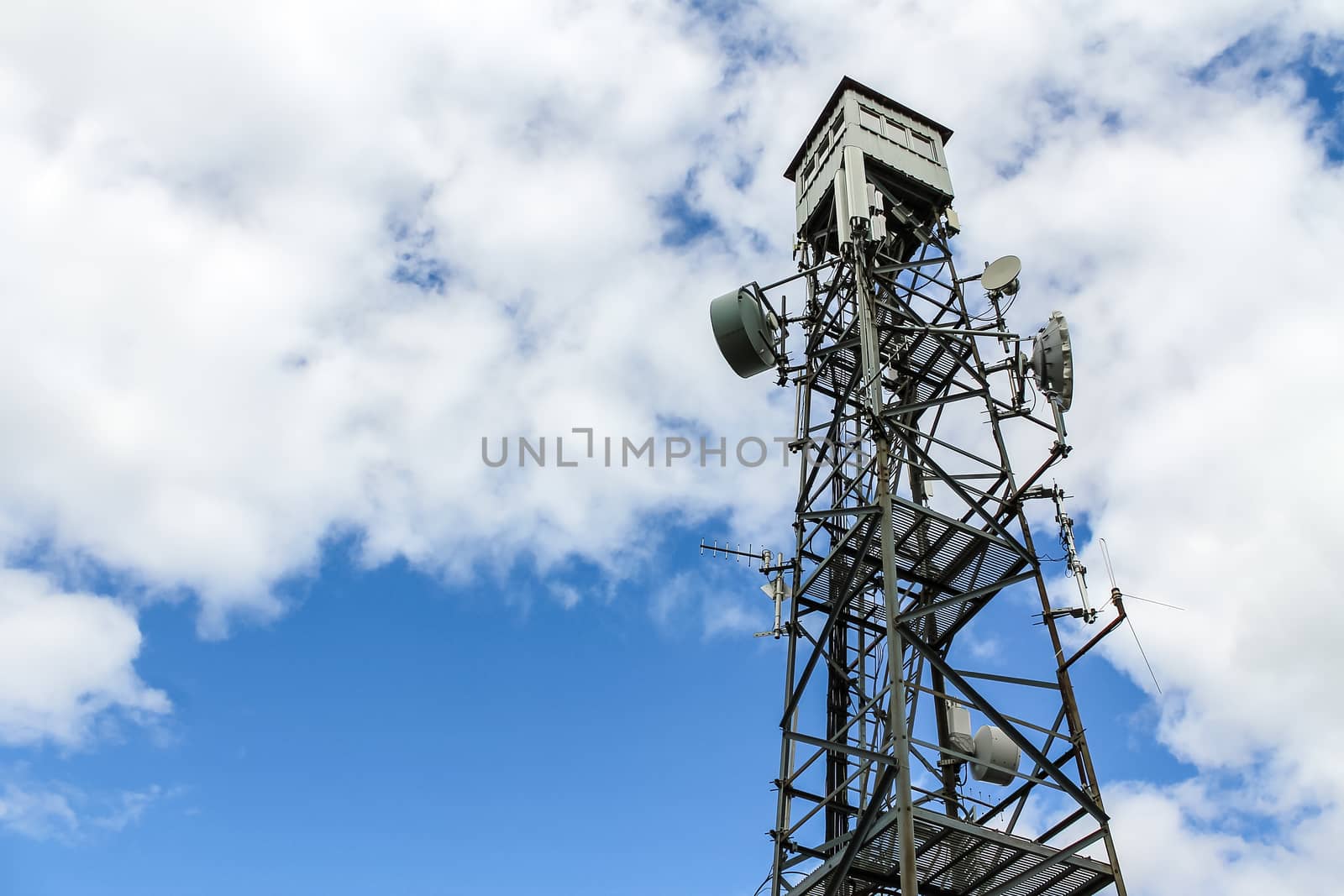 Telecommunication tower against the white clouds