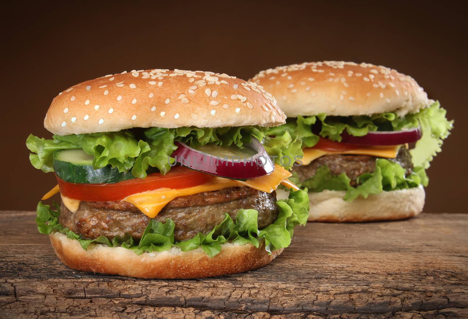 Two delicious hamburgers on wood background.