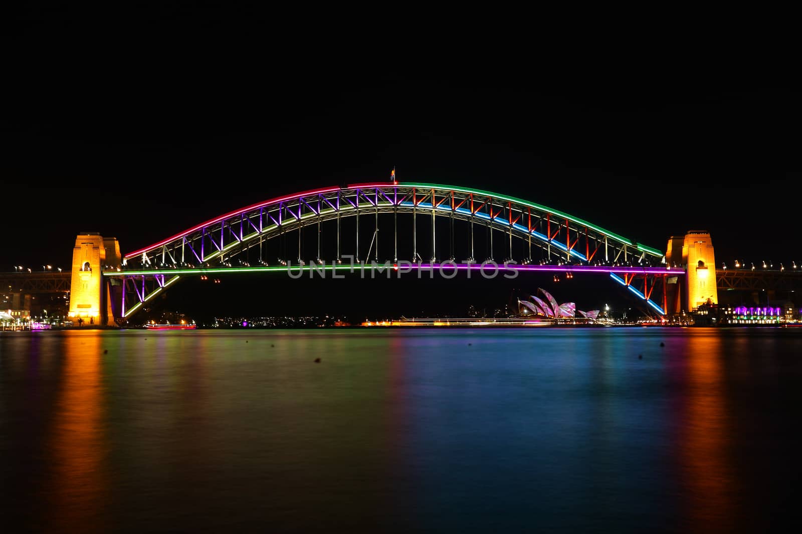 SYDNEY, AUSTRALIA - JUNE 2, 2014; The Sydney Harbour Bridge illuminated in beautiful colorus of magenta pink, purple, red, green, blue during Vivid Annual Festival.  Sydney Opera House in distance.  Long exposure.
