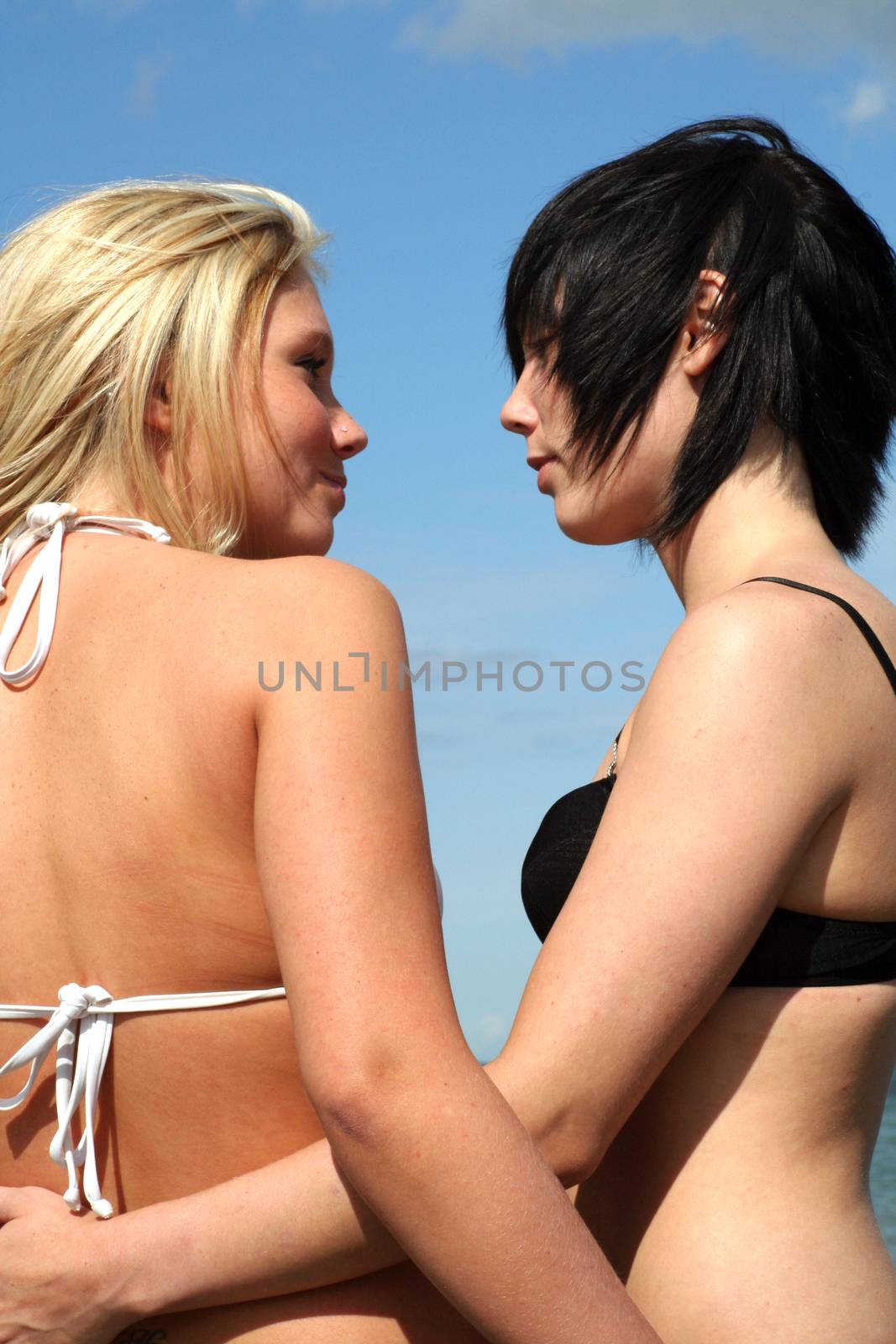 two women at the Beach holding each other, flirting