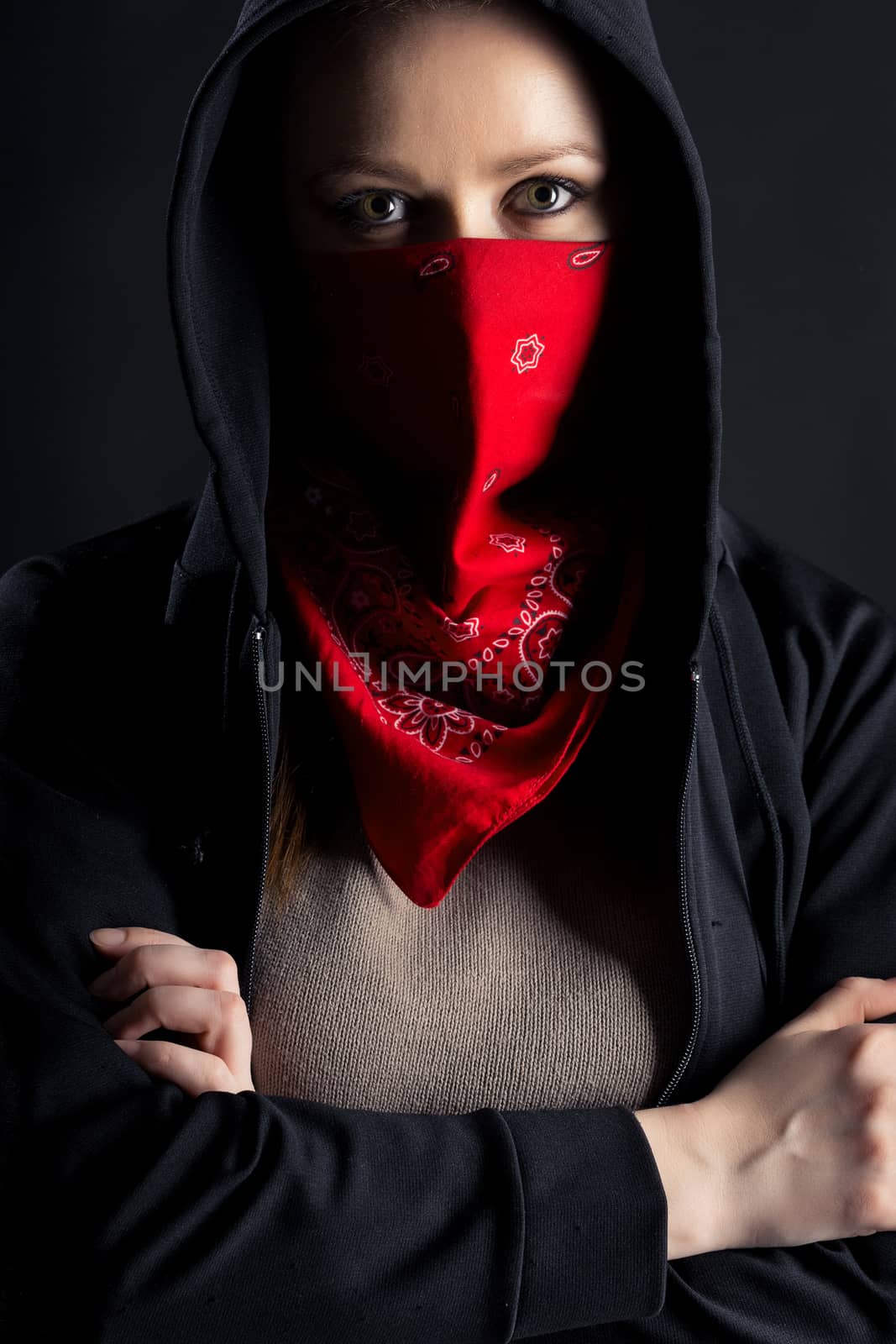 On a black background girl formidable form in black hood with a red shawl on his face