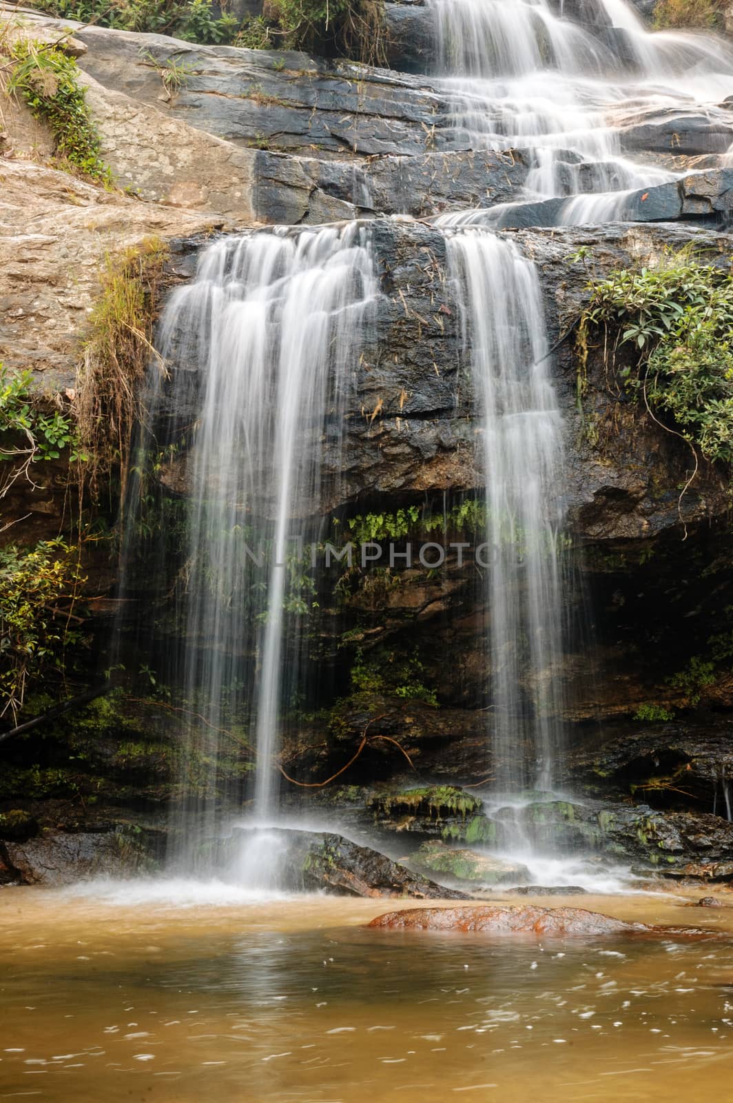 Beautiful silky waterfall flow through stones.