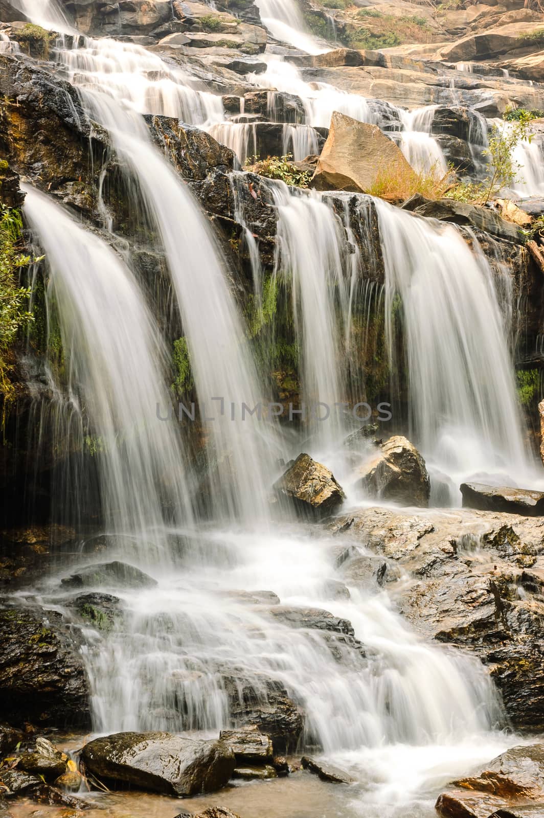 Beautiful silky waterfall flow through stones.
