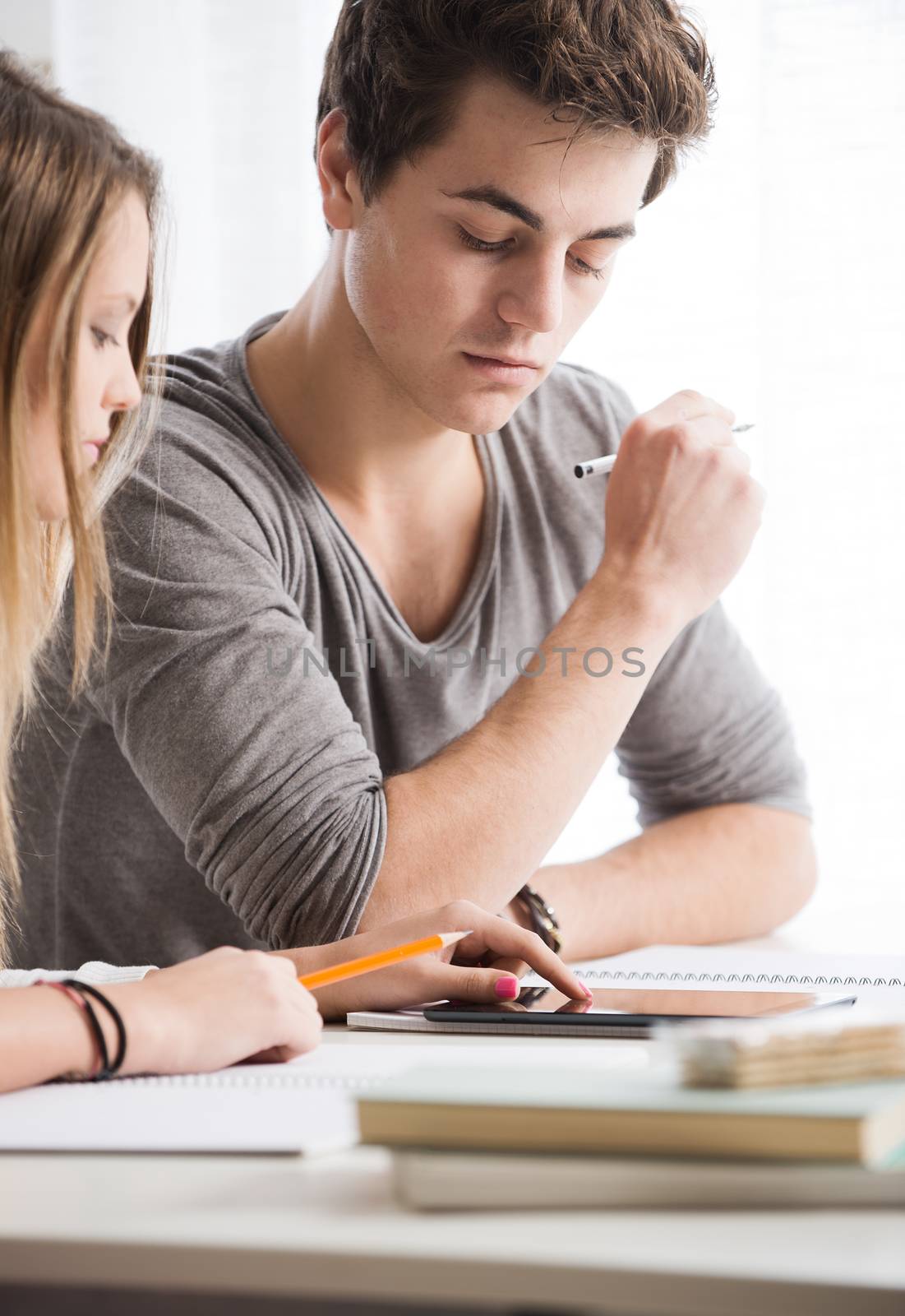 Teen boy and girl sitting together and studying 