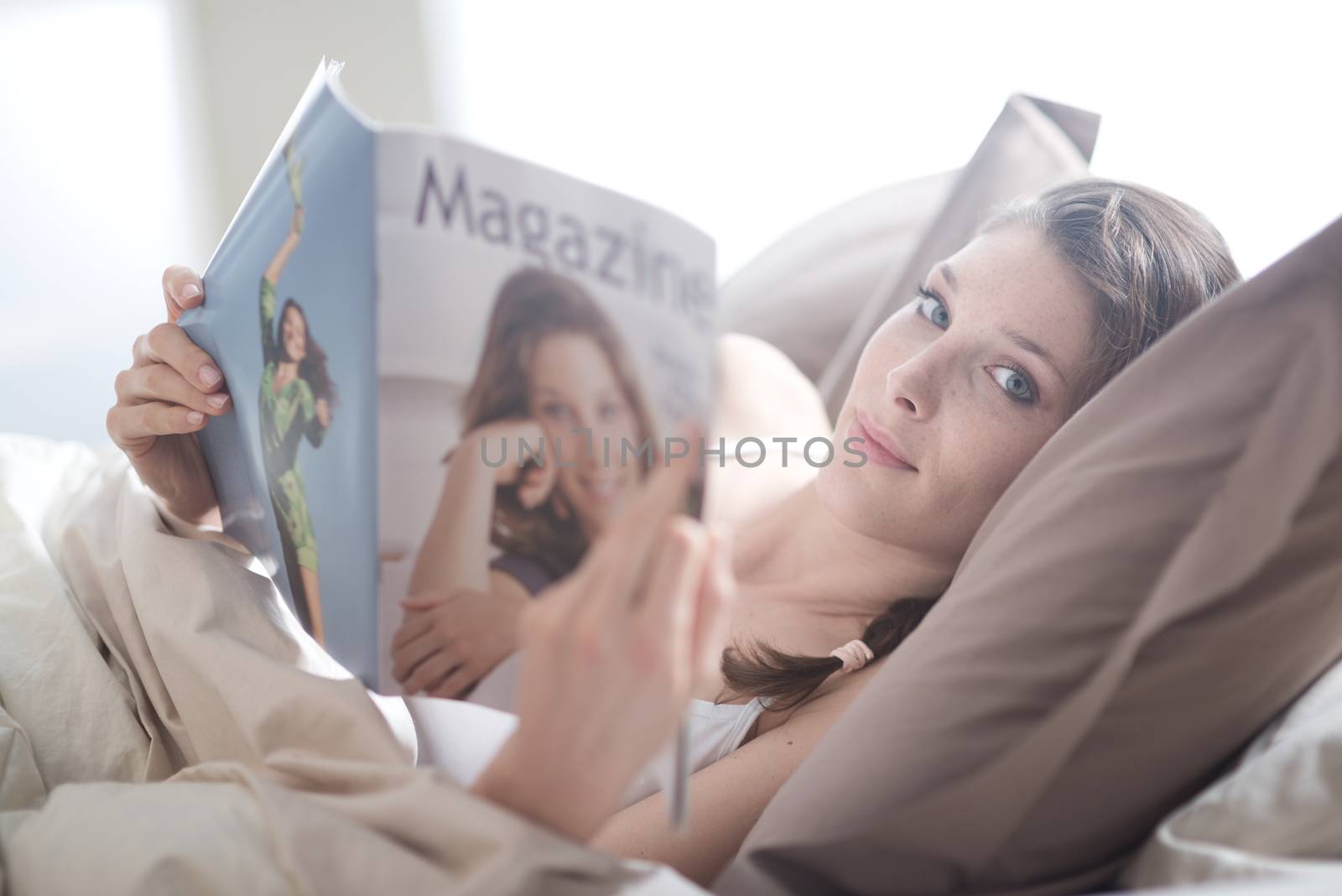 Woman lying in bed while reading a magazine