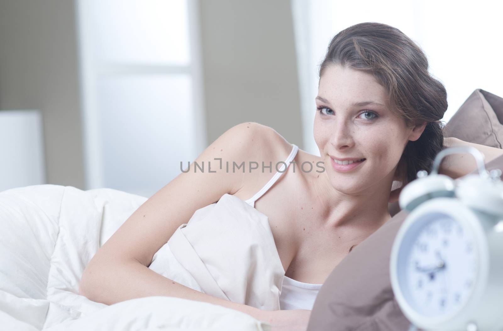 Young woman smiling while lying in bed 