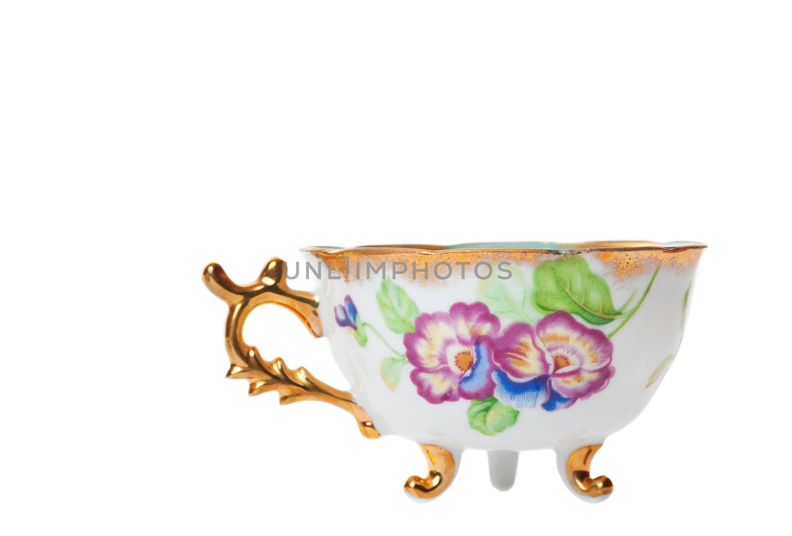 Antique footed tea cup with ornate handle.  Shot on white background.