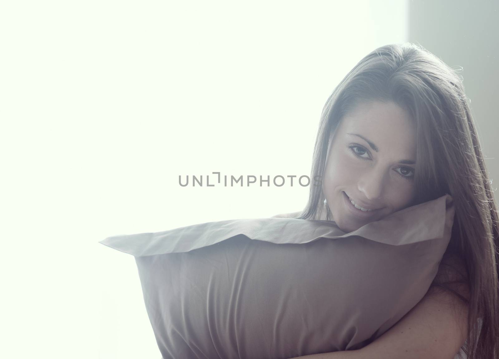 Young woman embracing her pillow in the morning