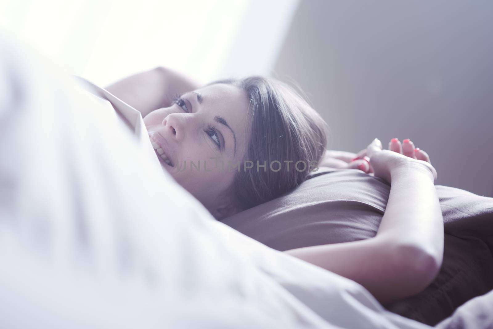 Young woman smiling while lying in bed 