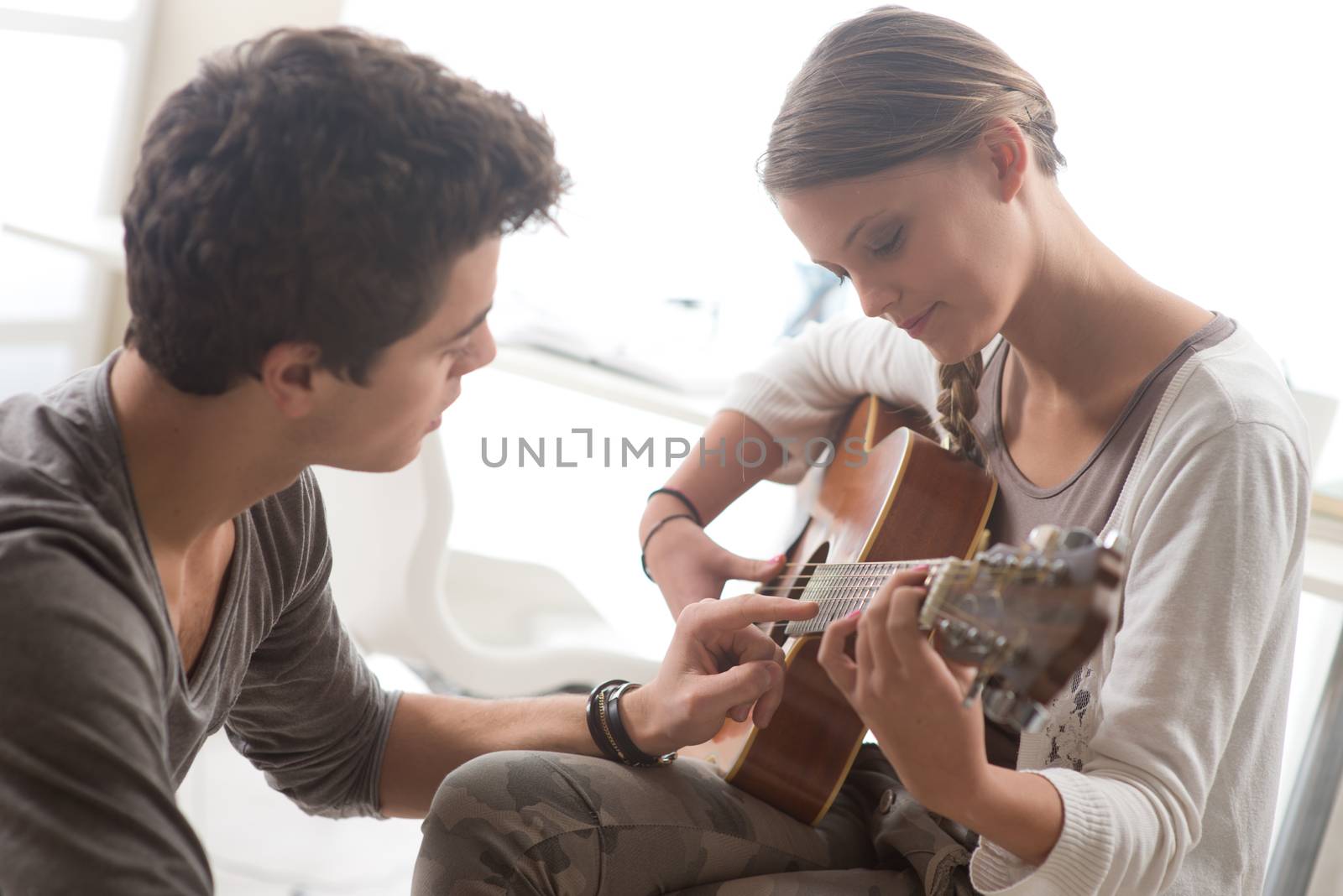 Young beautiful couple resting at home and playing guitar